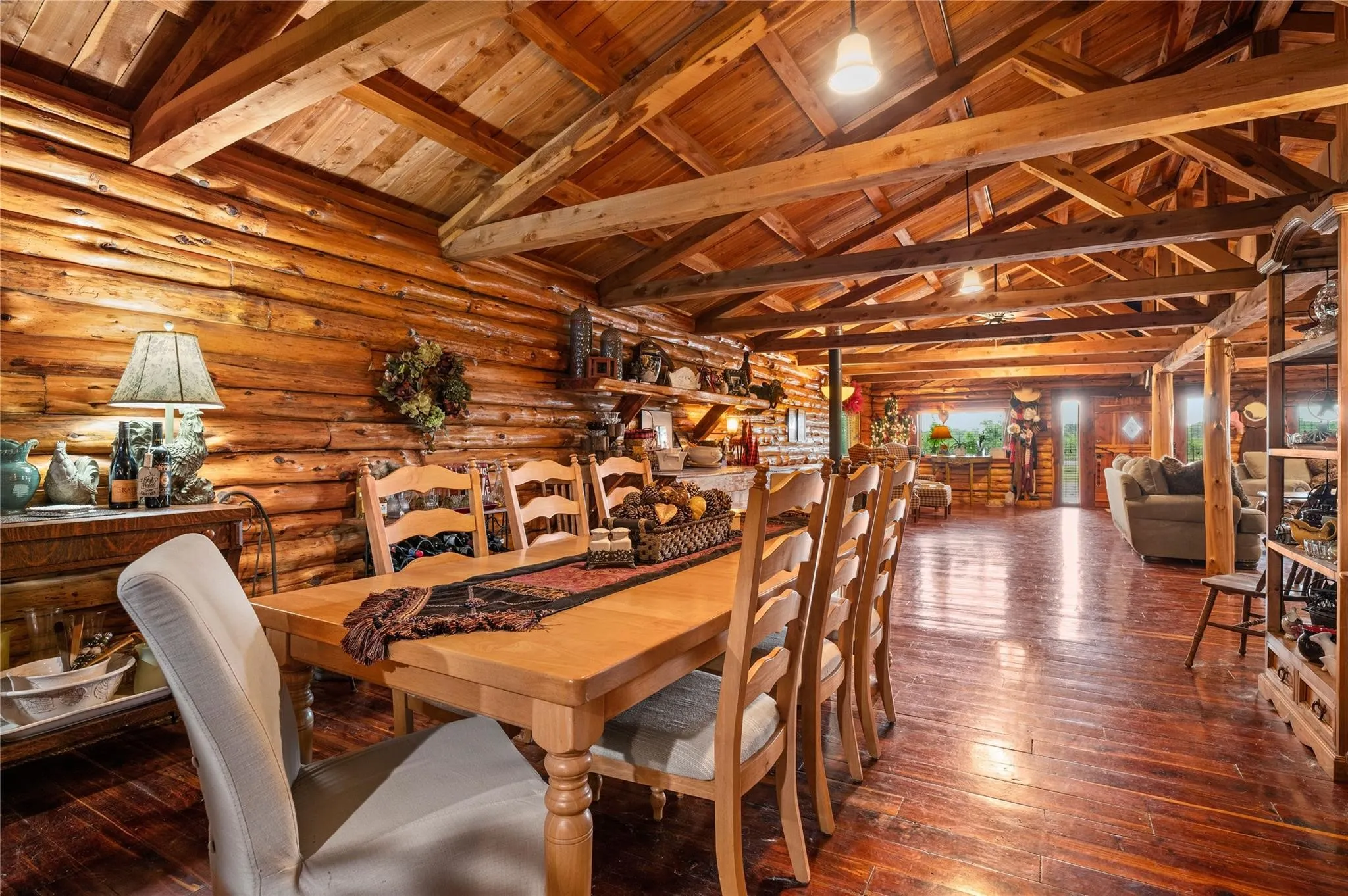 Looking towards the front door... Exposed wood beam ceiling, wood-finish flooring, wood plank walls, built-in shelving, and natural wood dining table.