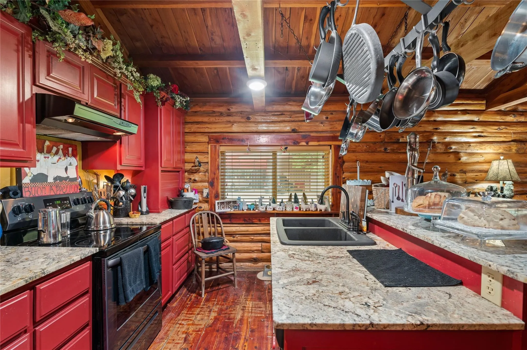 Kitchen featuring log walls, cedar flooring, red cabinetry, granite countertops, and a double basin sink.