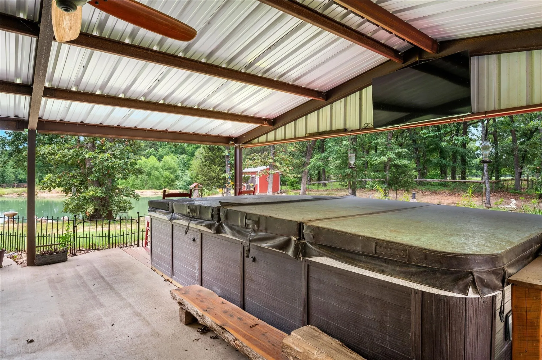 Covered patio with concrete flooring, integrated swim spa, and exposed beam ceiling with a mounted fan. Swim spa has new(2026) control panel (brains).