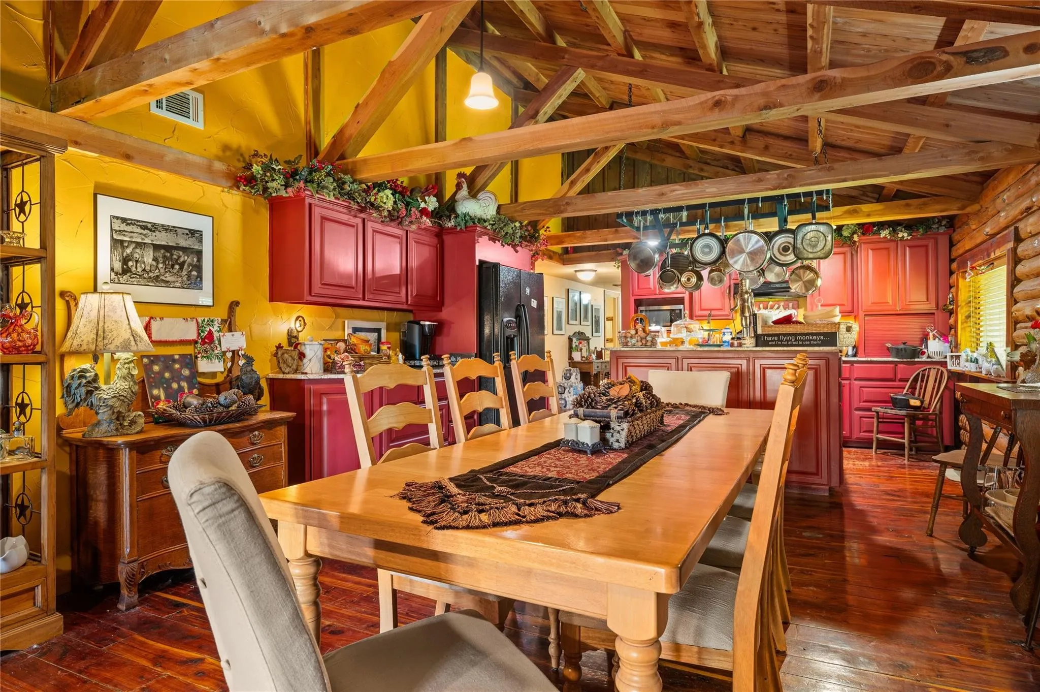 Vaulted wood-beam ceiling, wood-finish flooring, red cabinetry, and a kitchen island with built-in storage.
