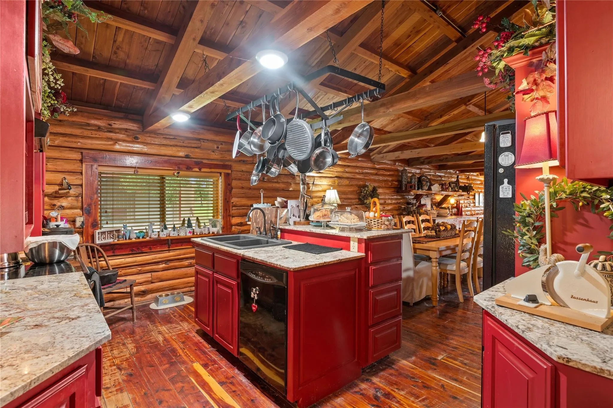 Kitchen featuring red cabinetry, granite-style countertops, wood-finish flooring, and a log wall construction.