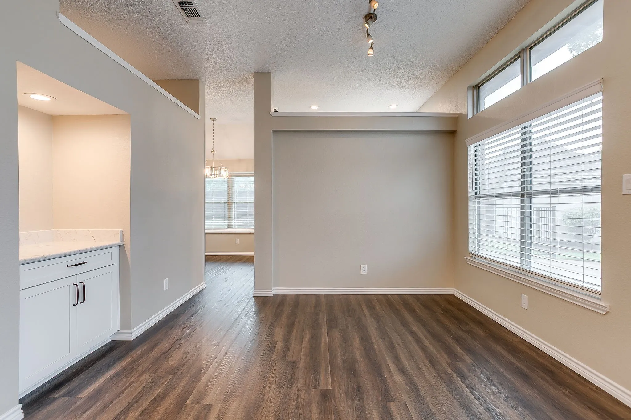Wood-finish flooring, built-in cabinetry with white finish, recessed lighting, and large windows with transom elements