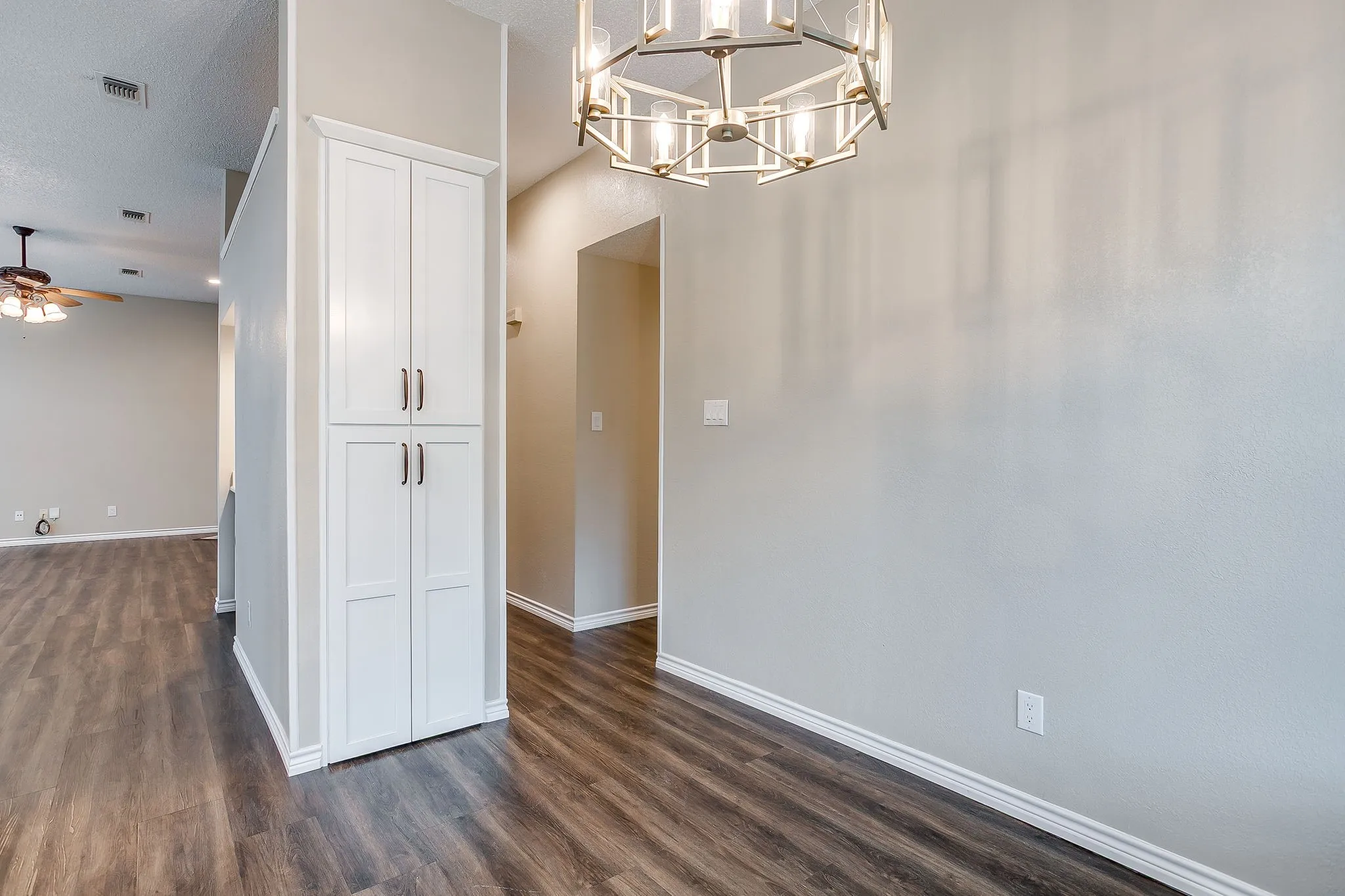 Wood-finish flooring, built-in storage cabinetry, contemporary chandelier, and recessed lighting