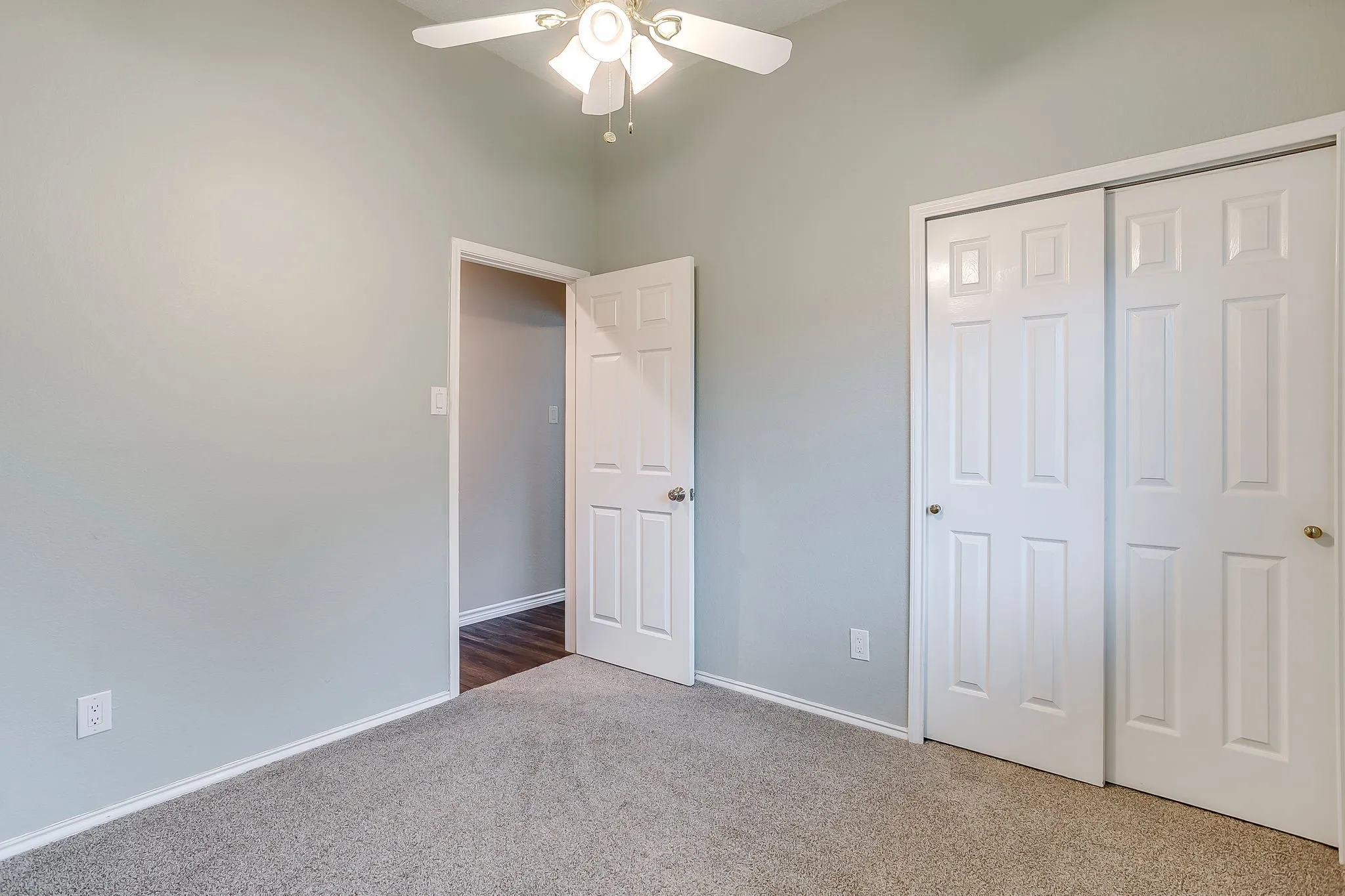 Carpeted flooring, ceiling fan with integrated lighting, paneled interior doors, and sliding closet doors