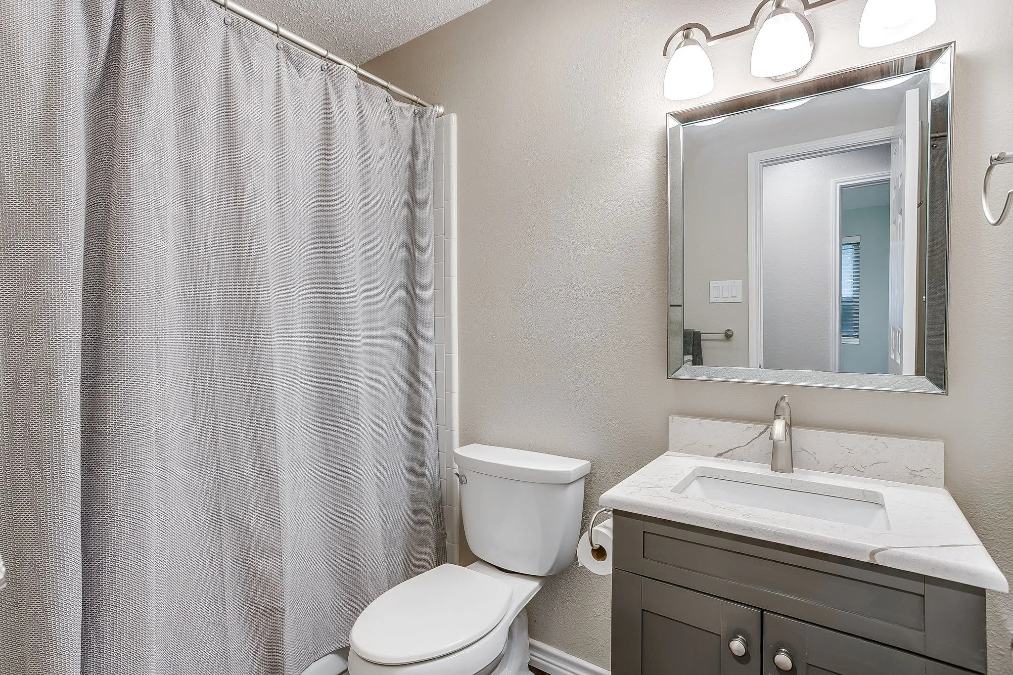 Vanity with stone countertop, undermount sink, and brushed nickel hardware