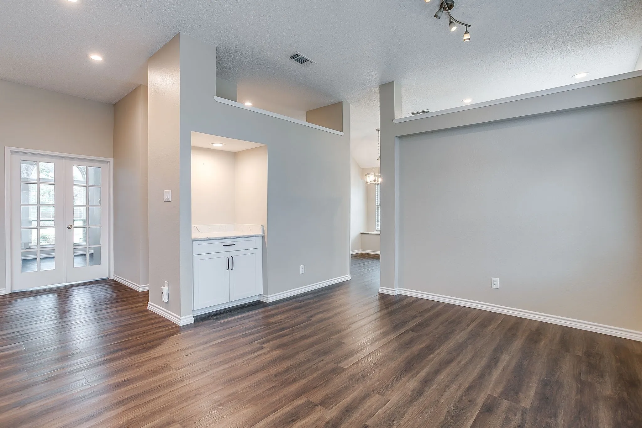 Wood-finish flooring throughout, recessed lighting, and a built-in cabinet with a countertop