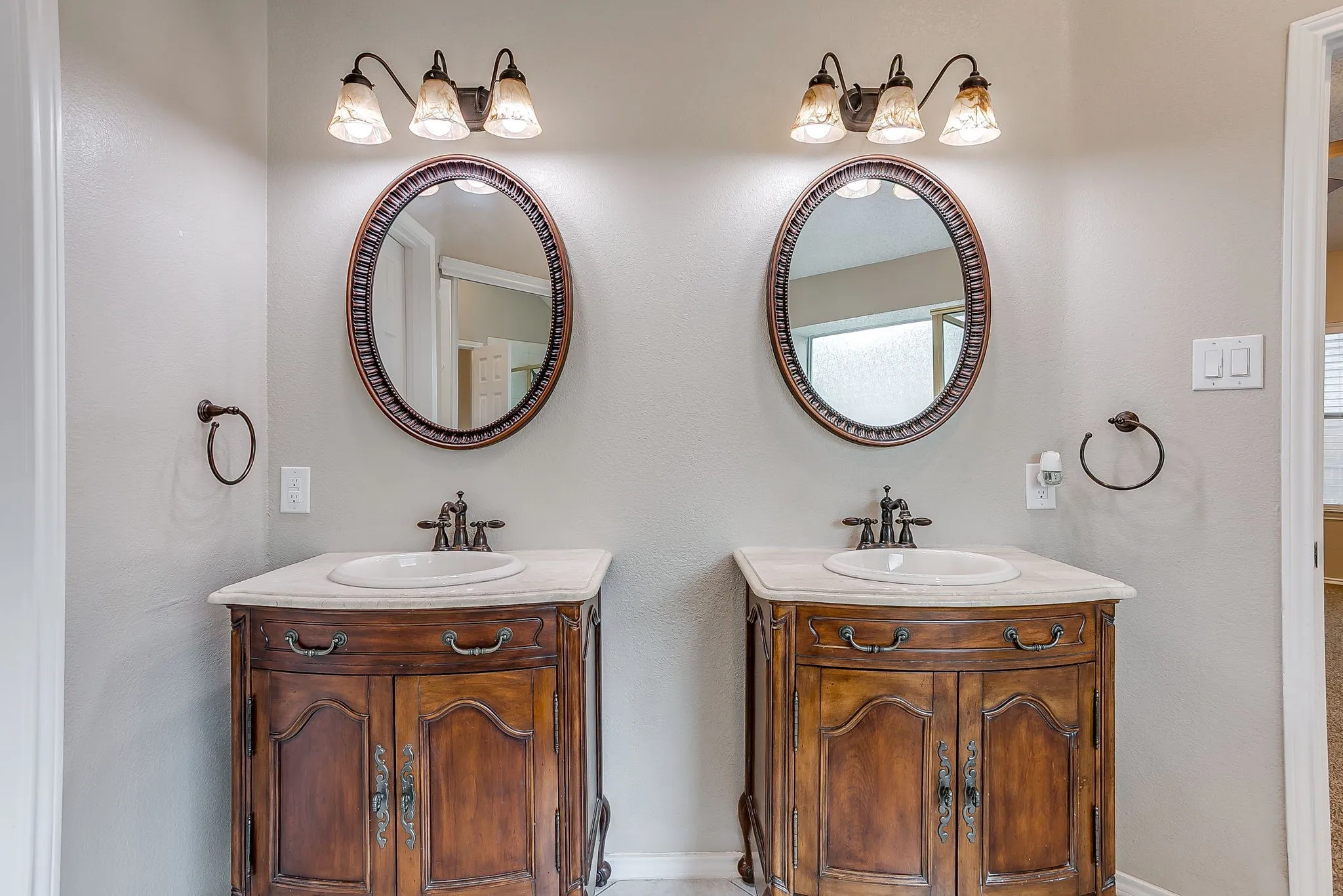 Double vanity featuring wood-finish cabinetry, oval undermount sinks, and stone countertops