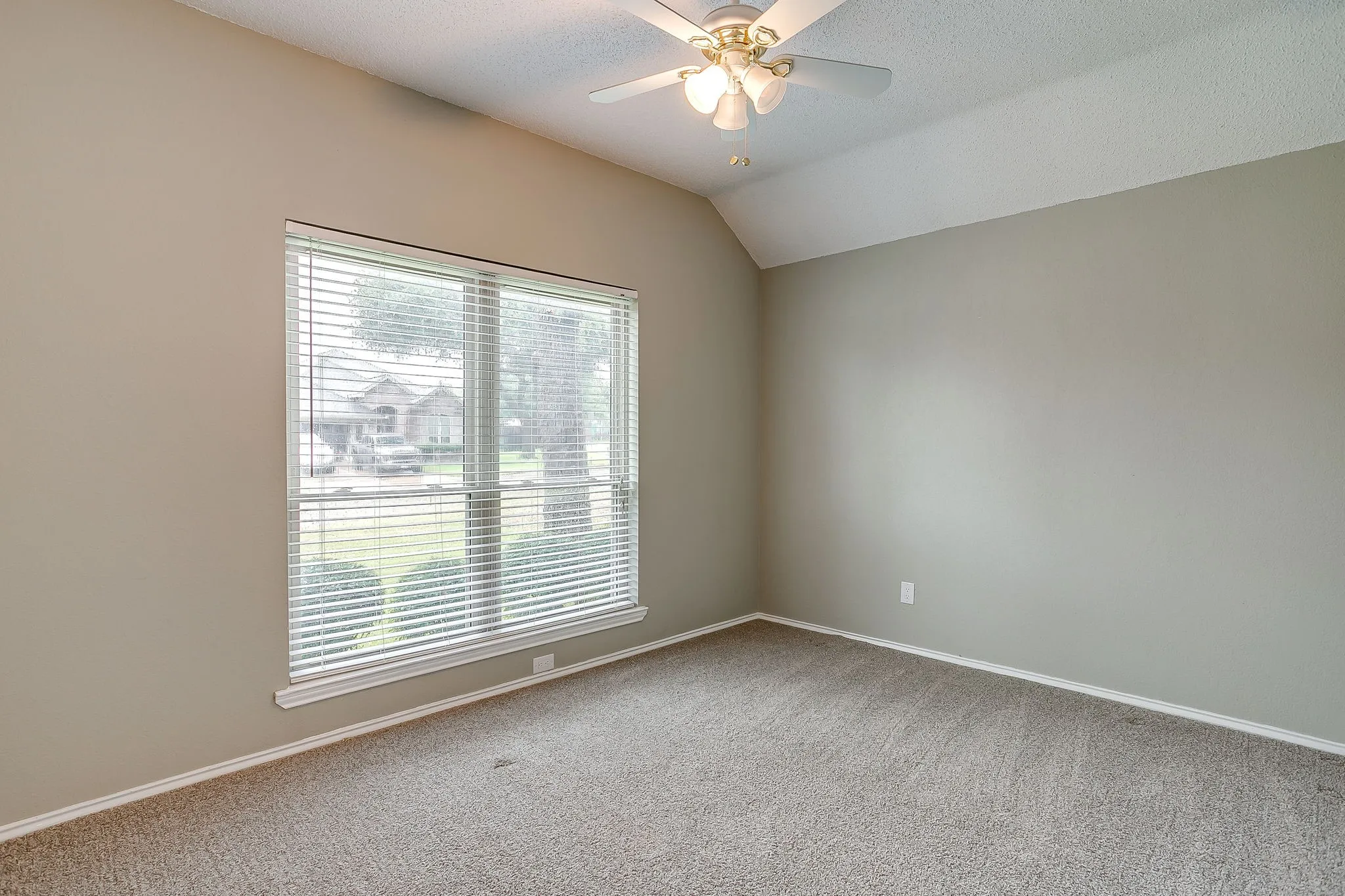 Vaulted ceiling with a ceiling fan light fixture, large window with blinds, and neutral tone walls