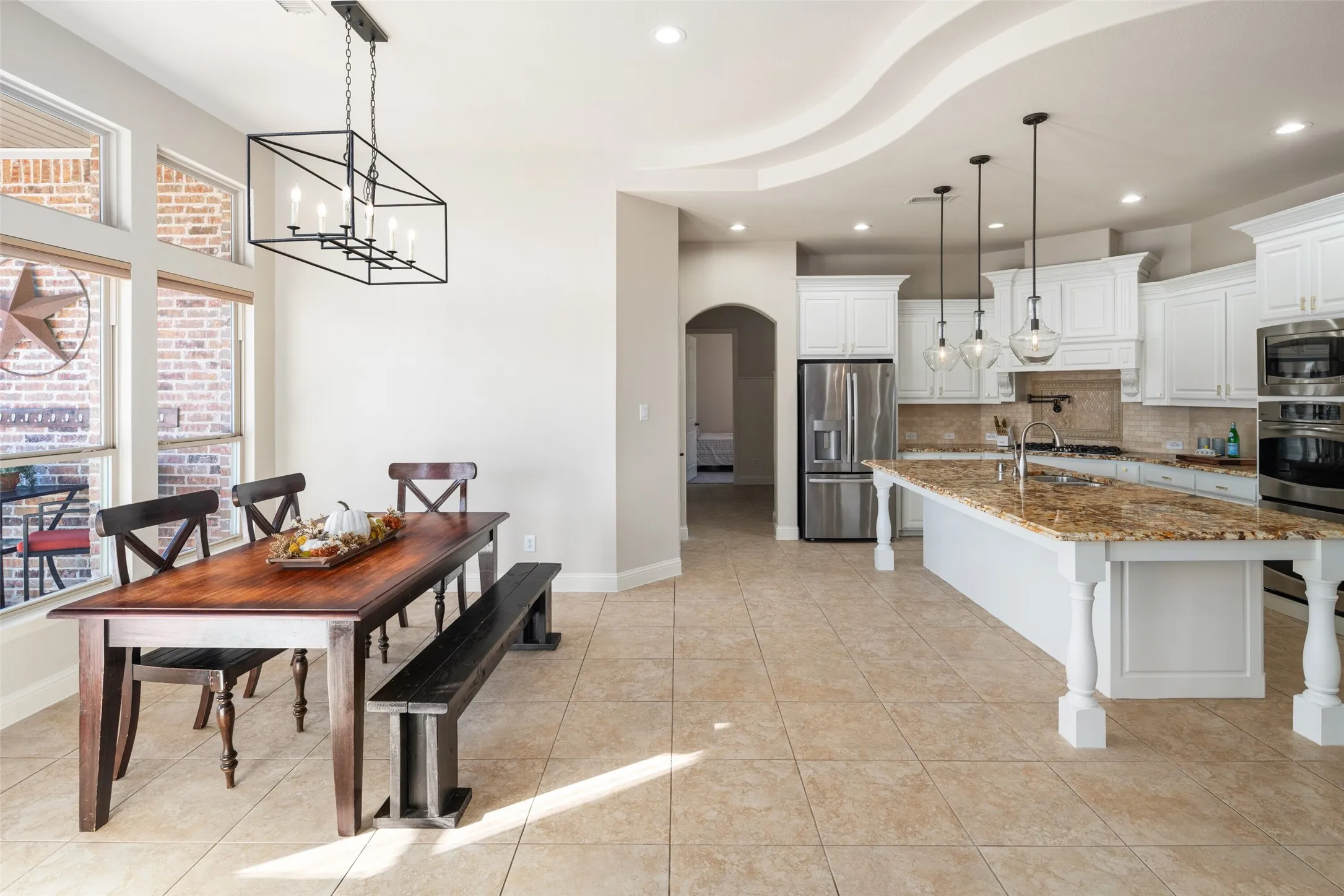 Expansive kitchen featuring a large island with stone countertop, white cabinetry, and stainless steel appliances