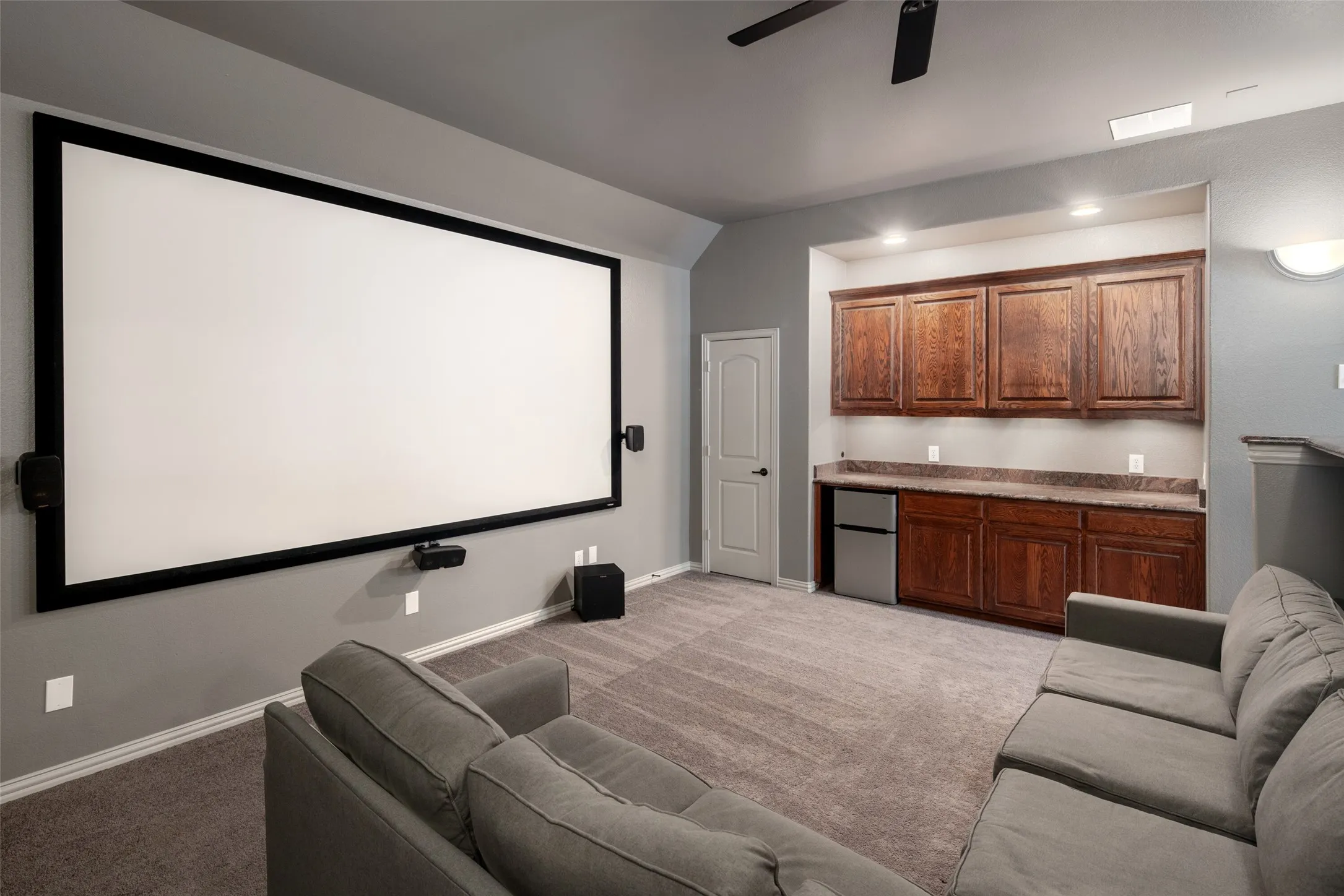 Integrated projection screen, built-in cabinetry with stone-finish countertop, recessed lighting, ceiling fan, and carpeted flooring
