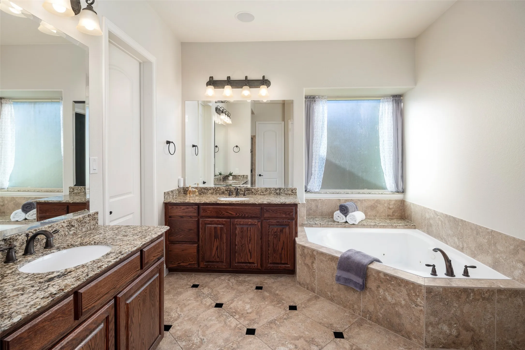 Dual vanity with granite countertops, rich wood cabinetry, and oil-rubbed bronze fixtures