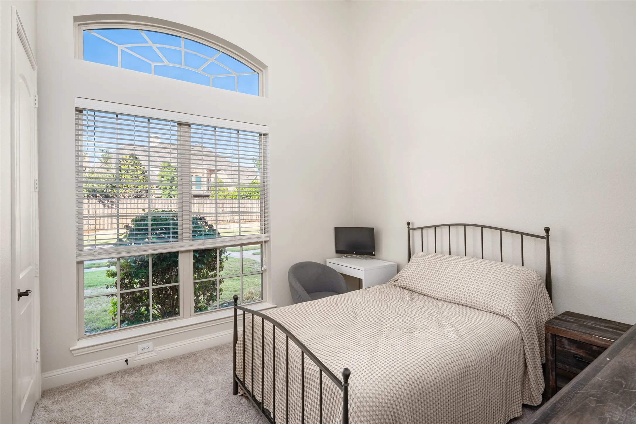 Arch-top transom window, double-hung windows with blinds, light gray wall paint, and gray carpet flooring