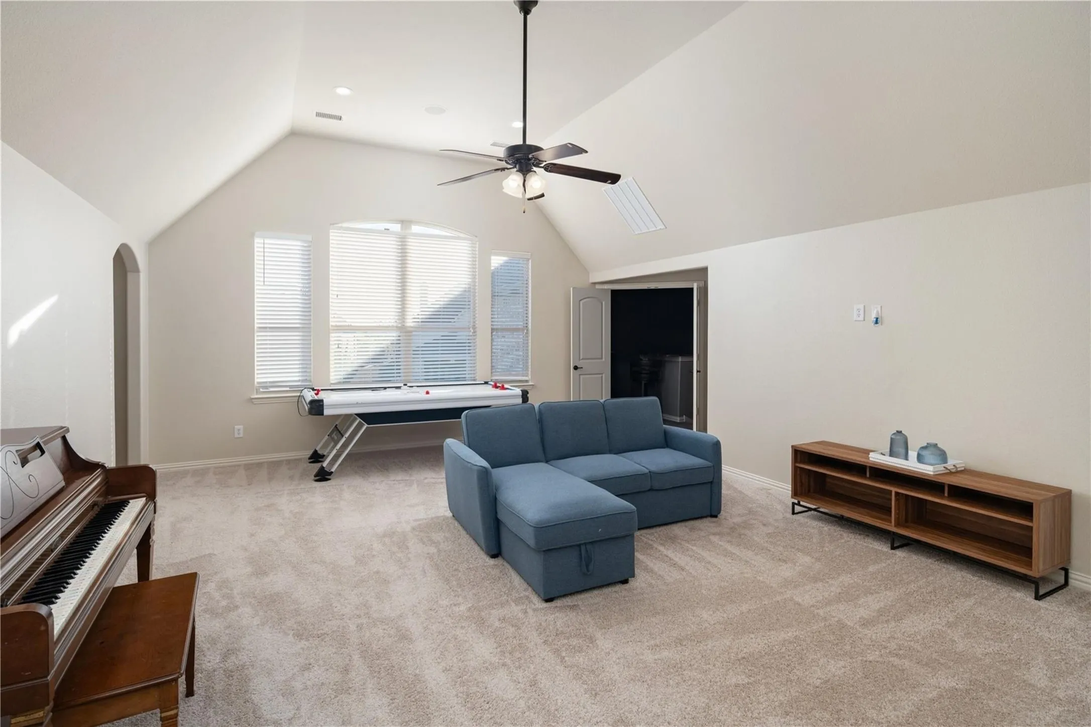 Vaulted ceiling with an integrated ceiling fan and recessed lighting, light-toned carpeting, arched doorway, and bay window with blinds