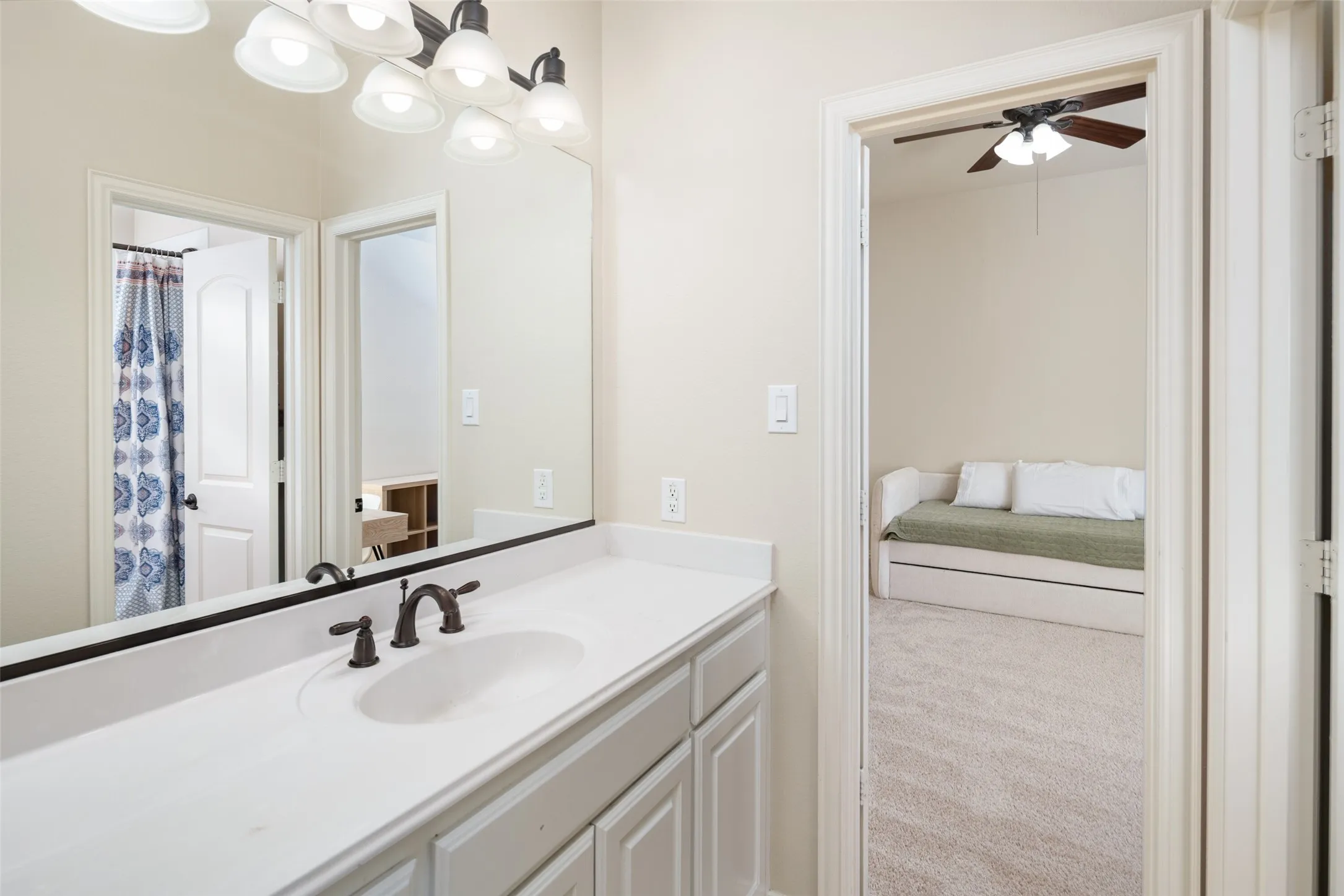 White vanity with a single basin sink, bronze-finish faucet, and an overhead multi-light fixture