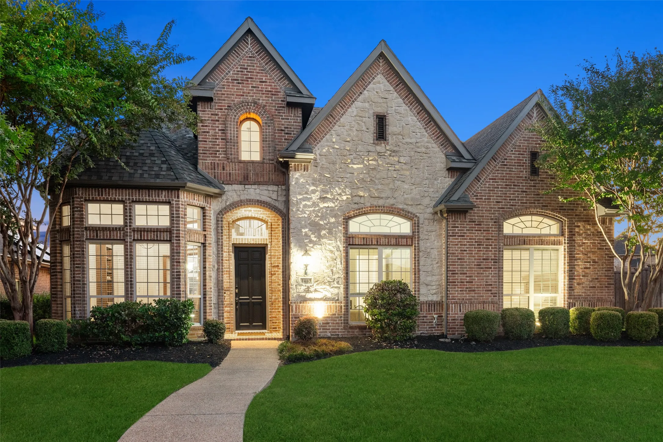 Brick and stone exterior with arched windows, gabled rooflines, and a curved paved walkway