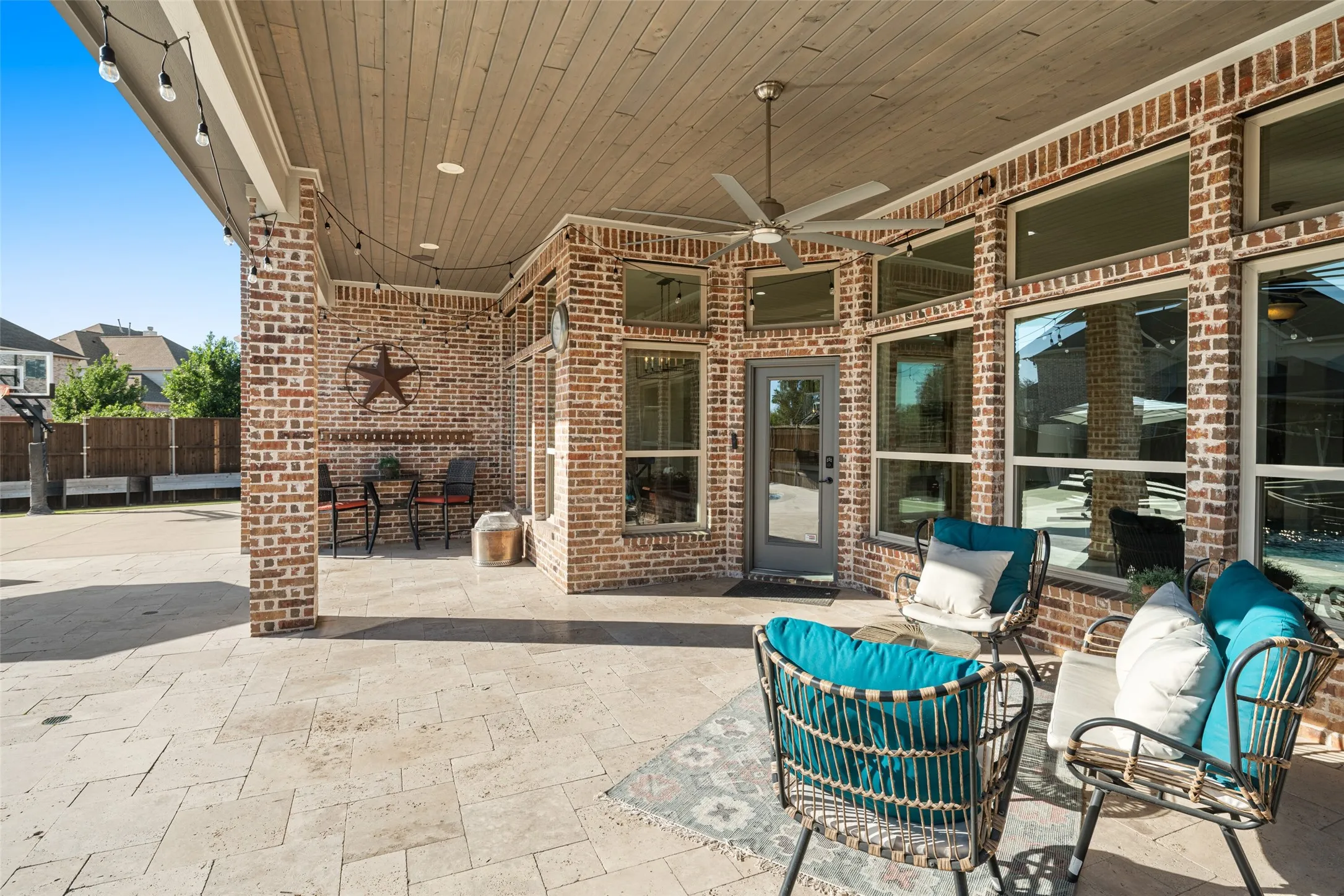 Covered patio featuring a wood-panel ceiling, ceiling fan, and string lighting
