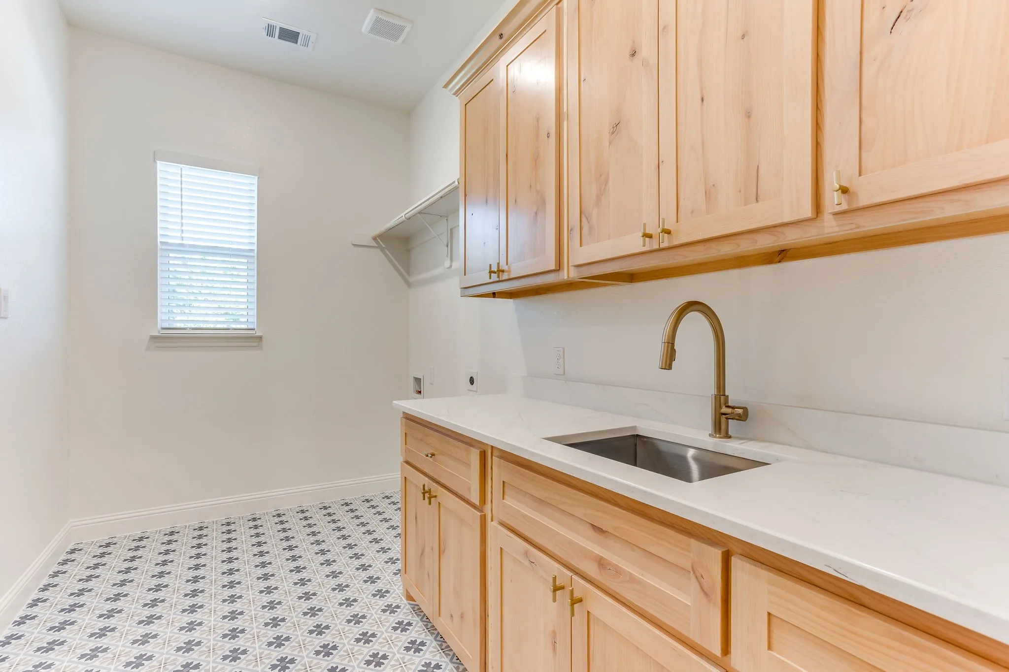 Laundry room includes tile floors, sink, custom cabinetry