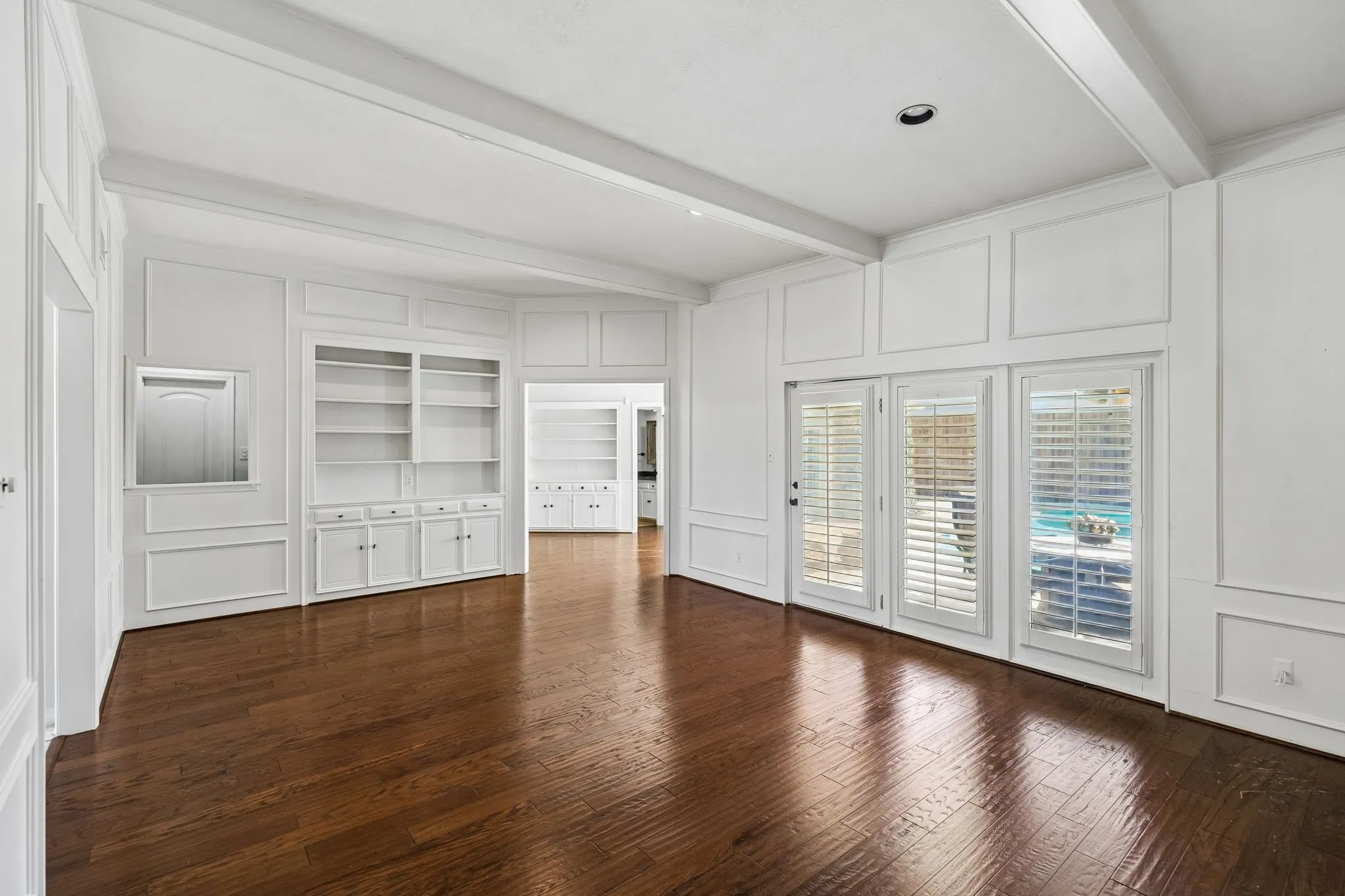 Elegant main living room showcasing hardwood flooring, custom built-in cabinetry with multiple storage drawers and cabinet doors, and an abundance of natural light