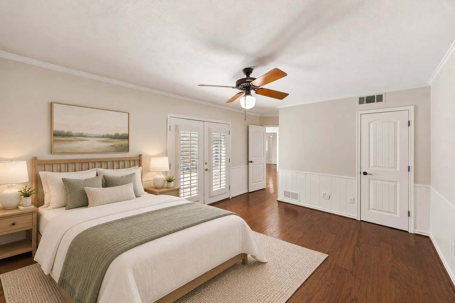 Spacious guest bedroom featuring hardwoods, french doors, walk-in closet and en suite bath. This photo is virtually staged.