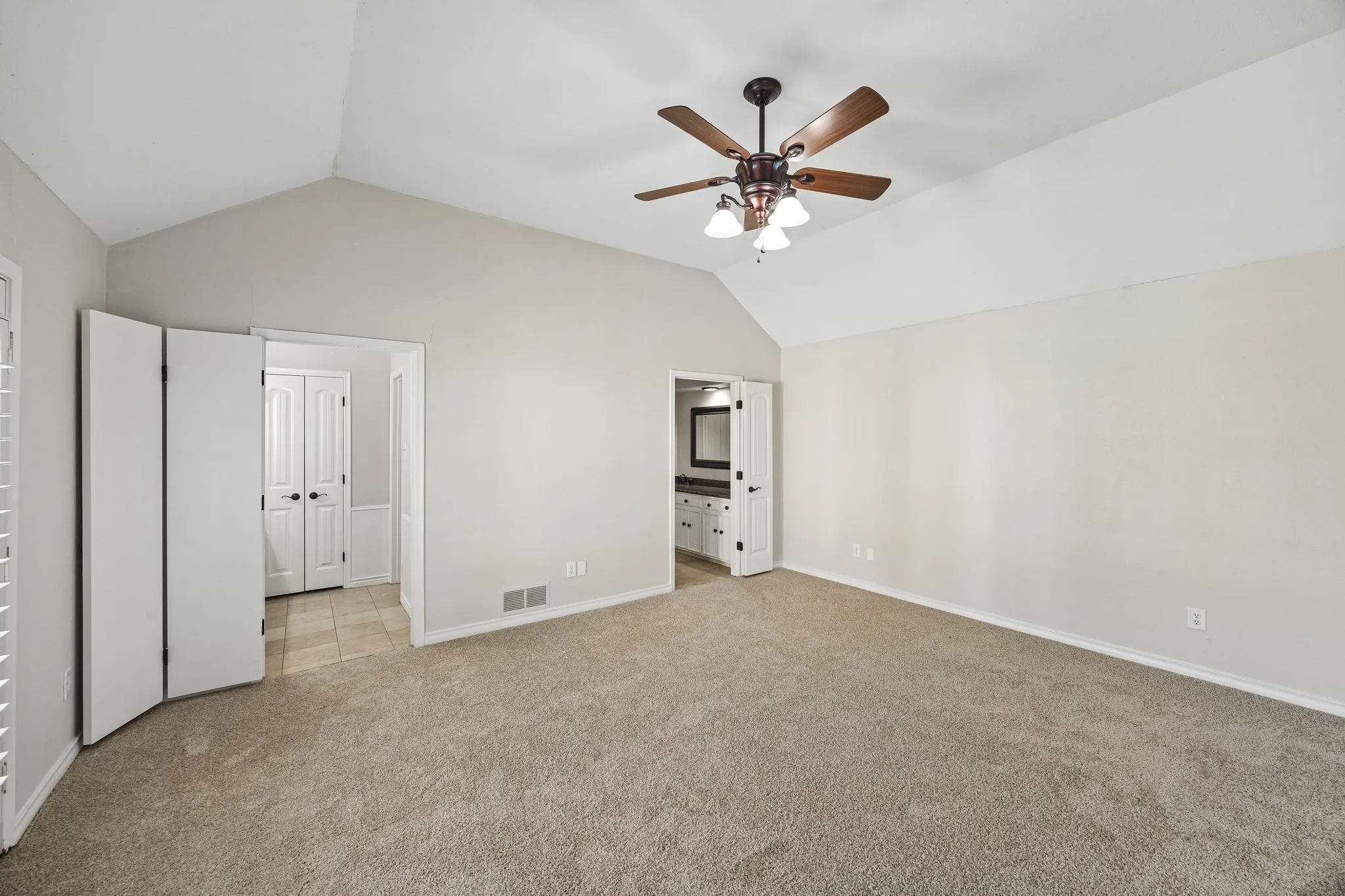 Spacious primary bedroom featuring vaulted ceilings, new carpet, and ensuite bath with separate vanities.