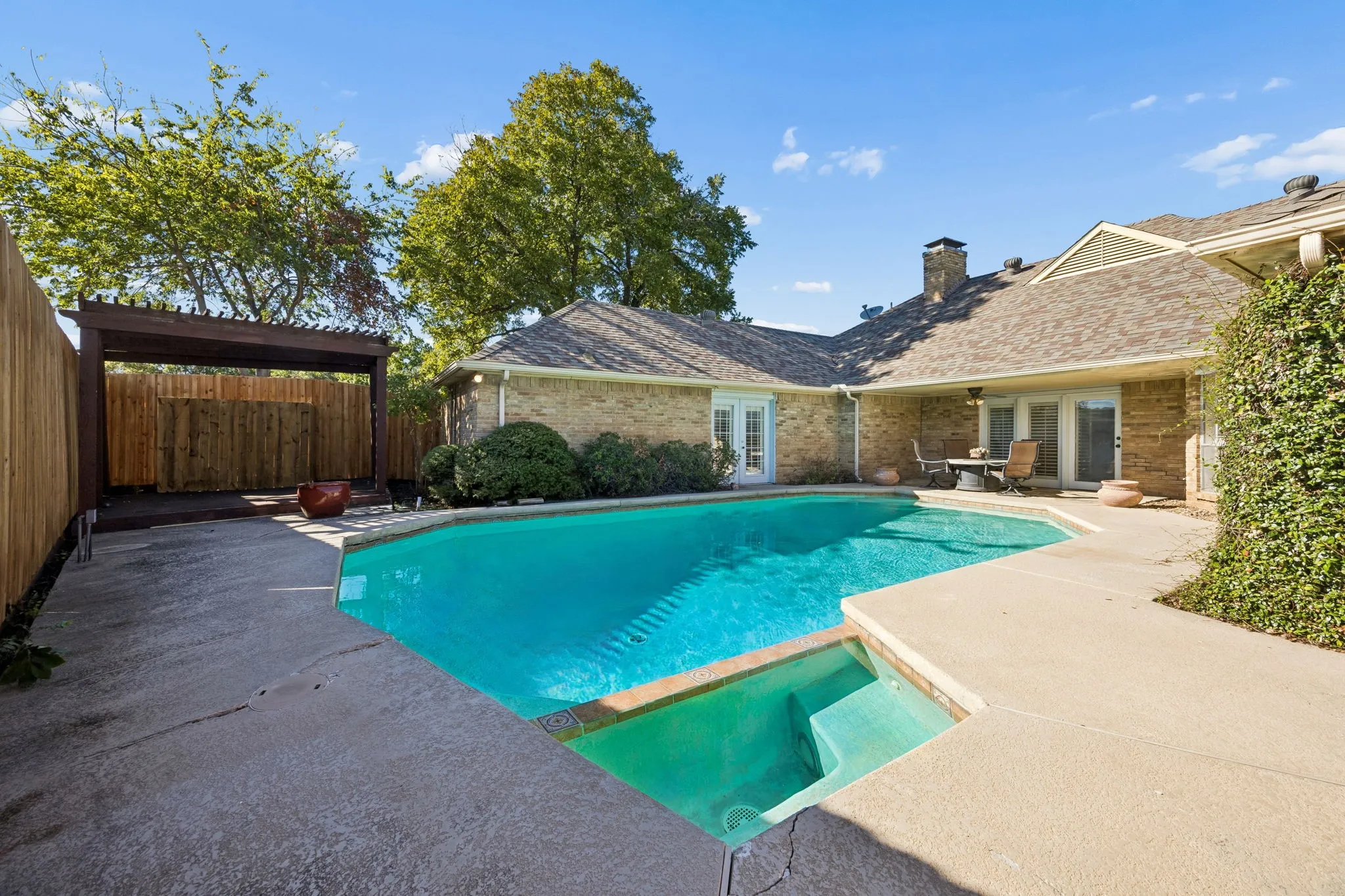 Inviting swimming pool with integrated spa, pergola, and new fence.