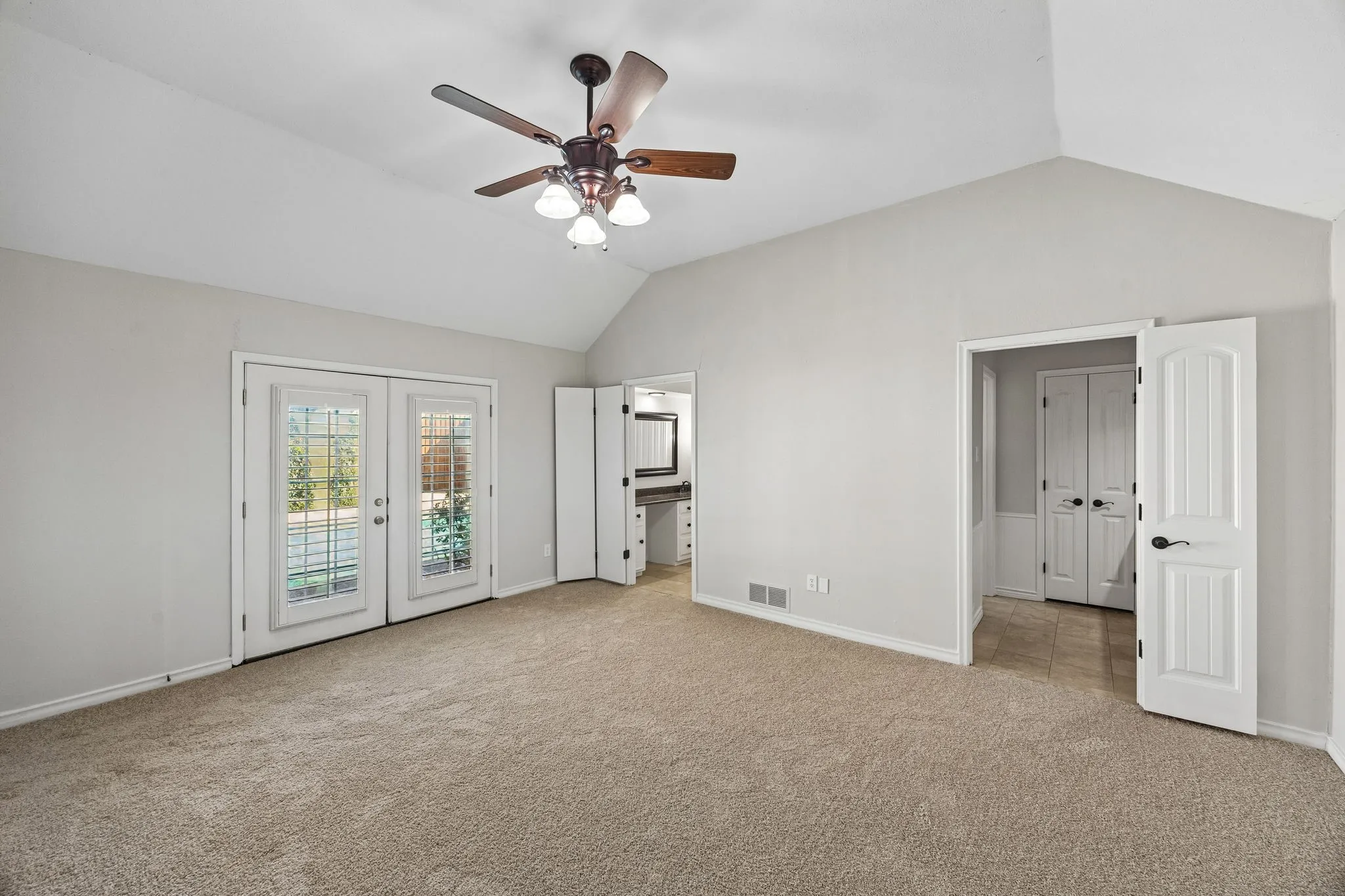 Spacious primary bedroom featuring vaulted ceilings, new carpet, and ensuite bath with separate vanities.