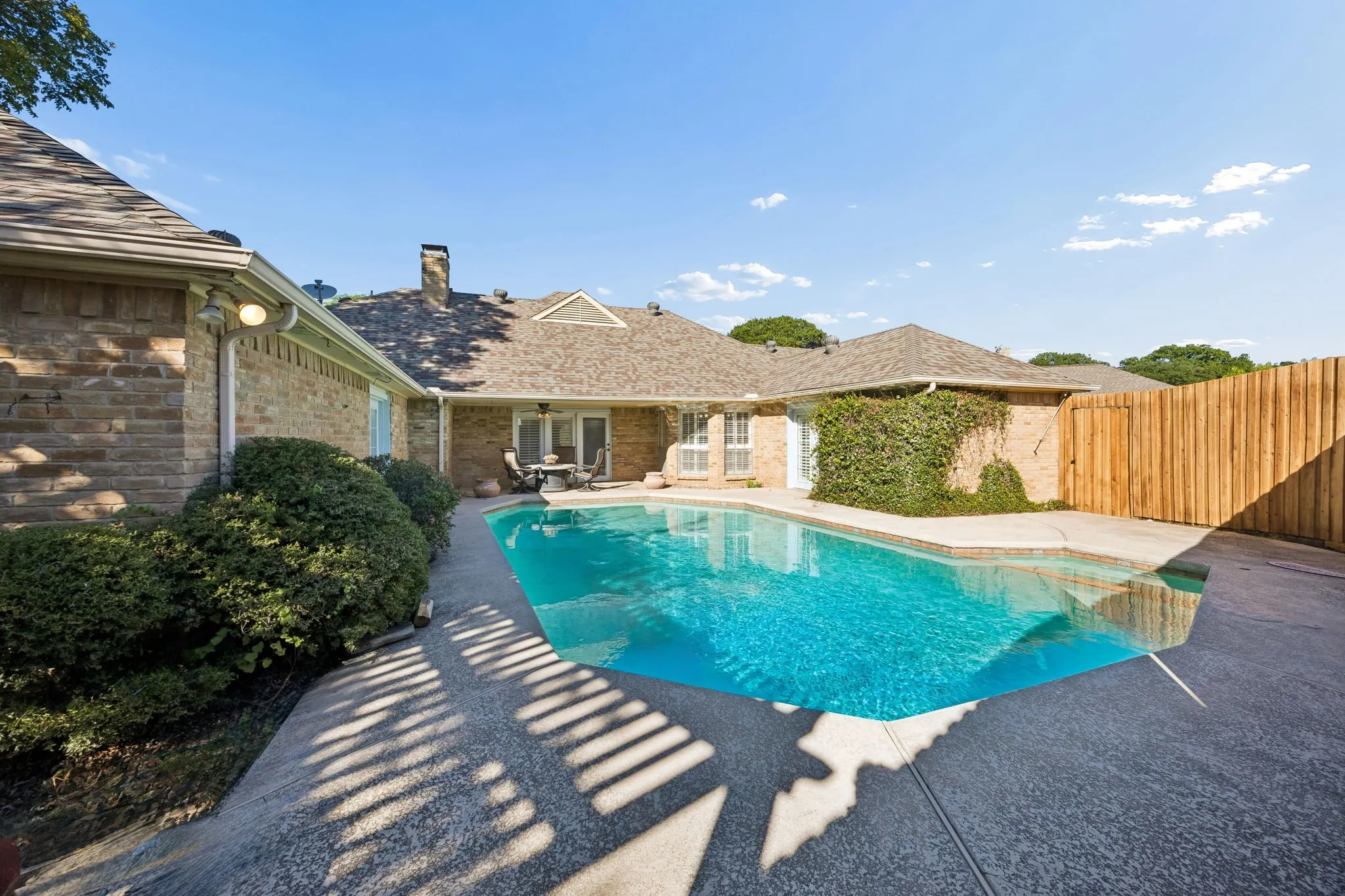 Inviting swimming pool with integrated spa, covered porch, and new fence.