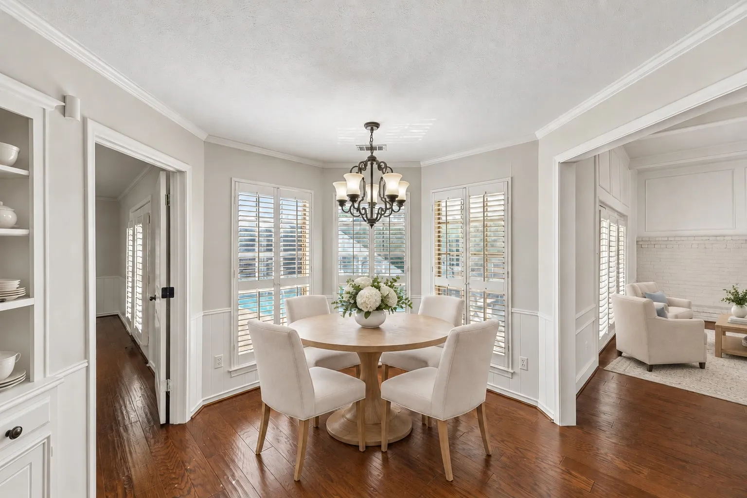 Eat-in kitchen breakfast area with built-in hutch, beautiful hardwoods, and overlooking pool. This photo is virtually staged.