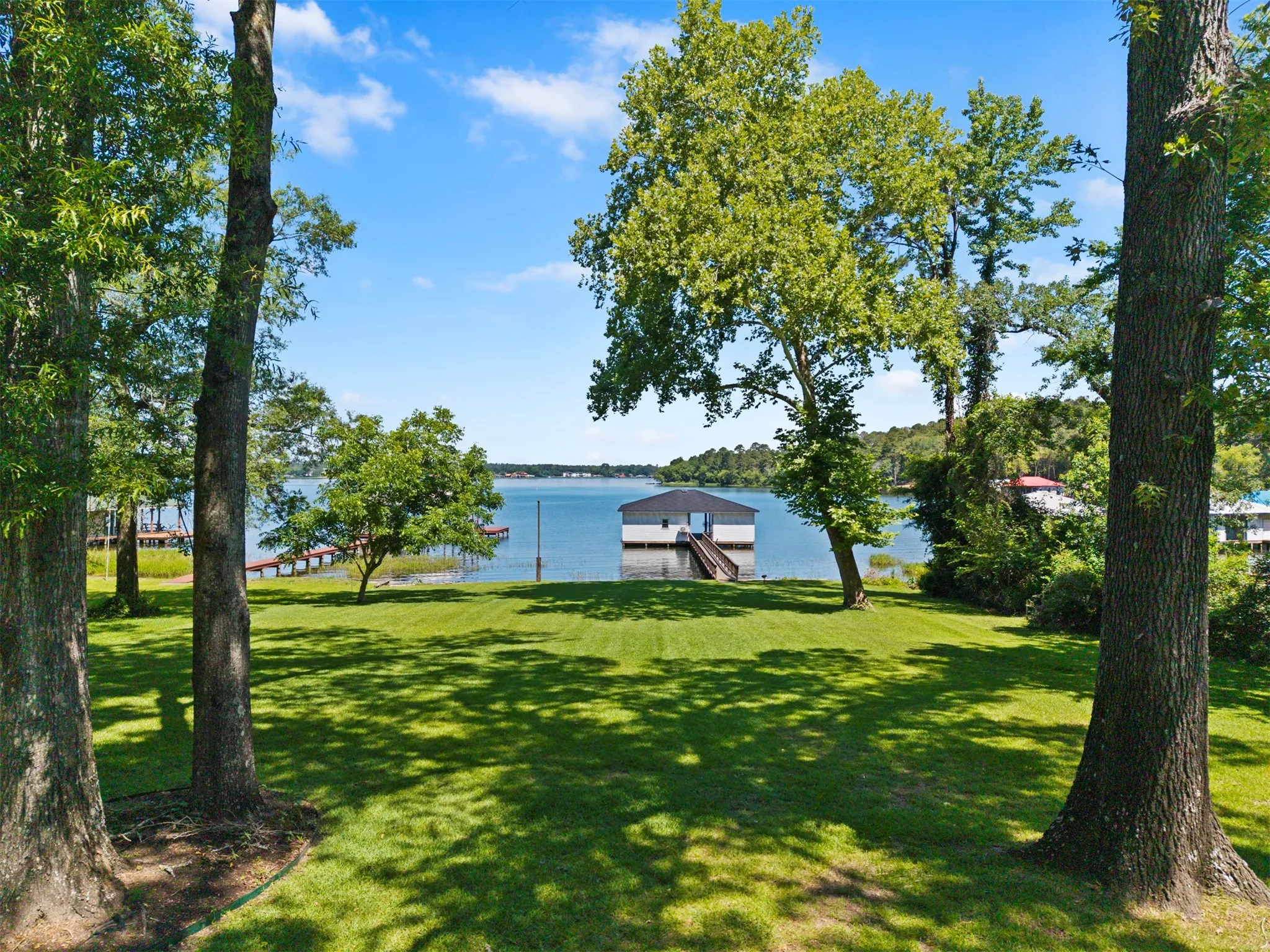 Expansive waterfront property featuring a boat house, private dock, and manicured lawn