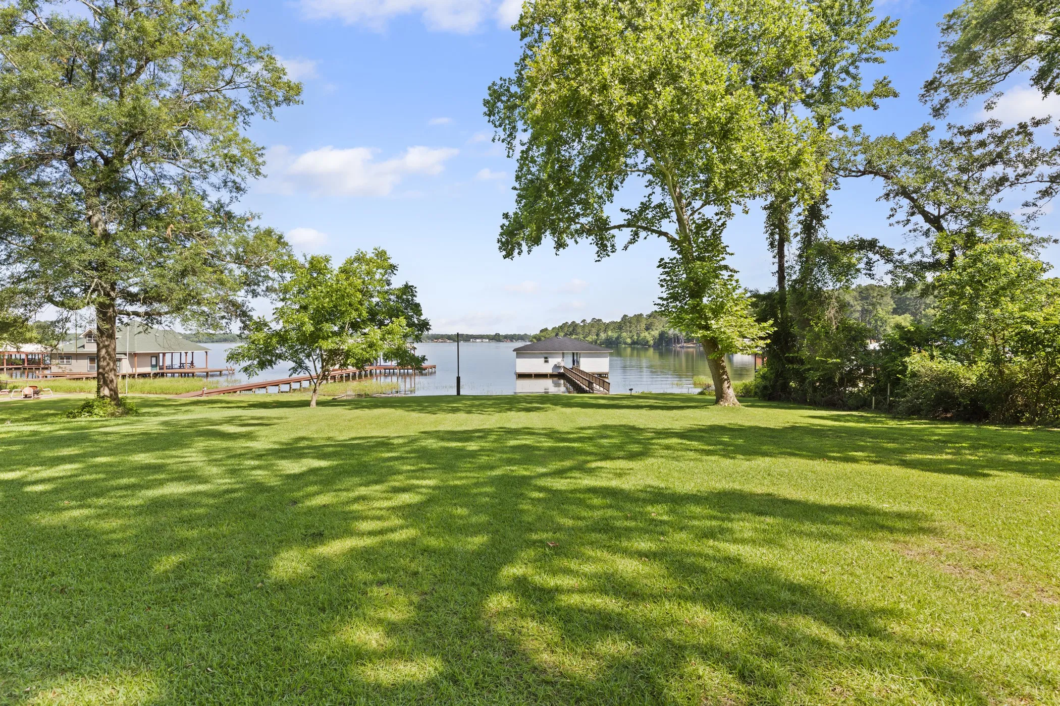 Expansive green lawn with mature trees and waterfront access