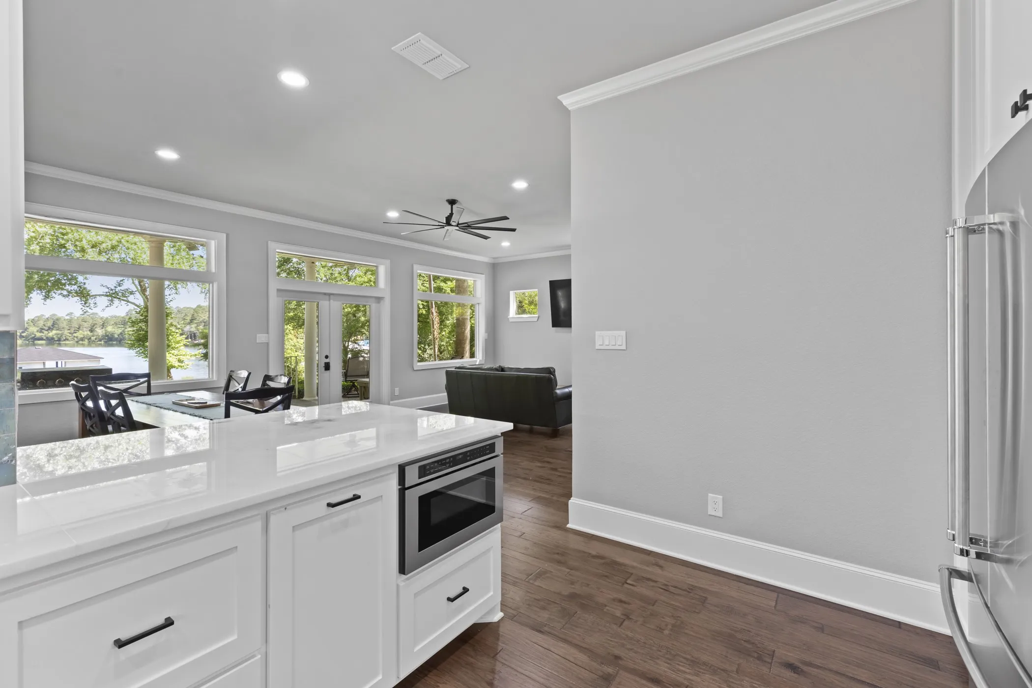 Open-concept living space featuring a white kitchen island with an integrated microwave, wood-finish flooring, and crown molding