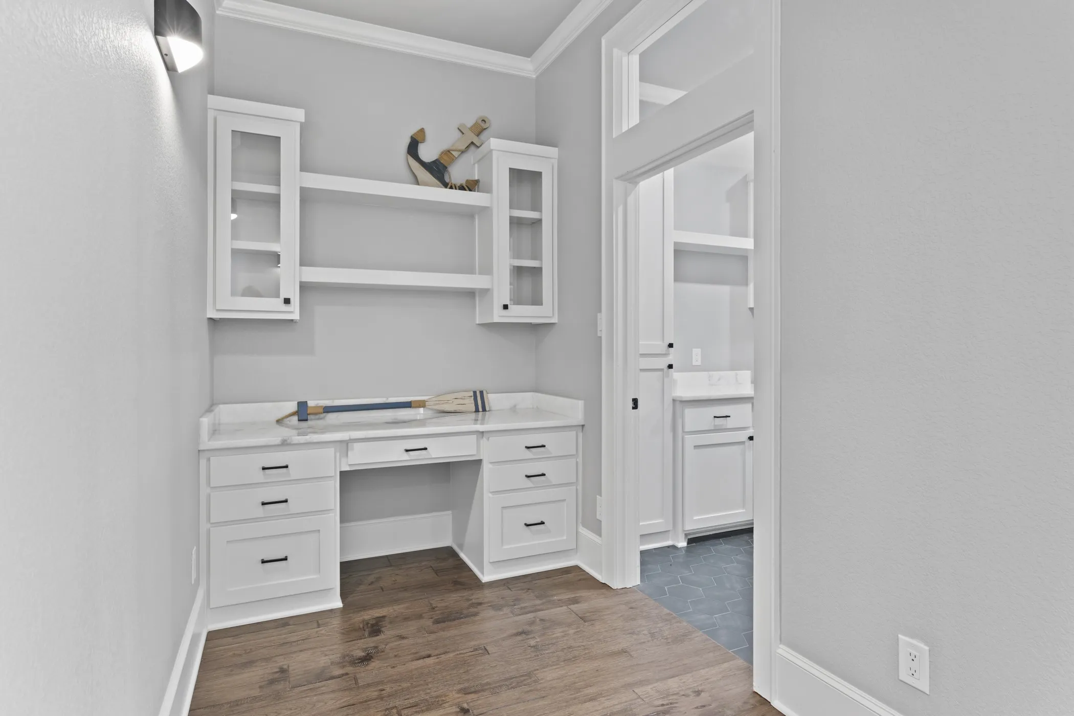 Built-in desk area featuring white cabinetry, a light-toned countertop, and open shelving