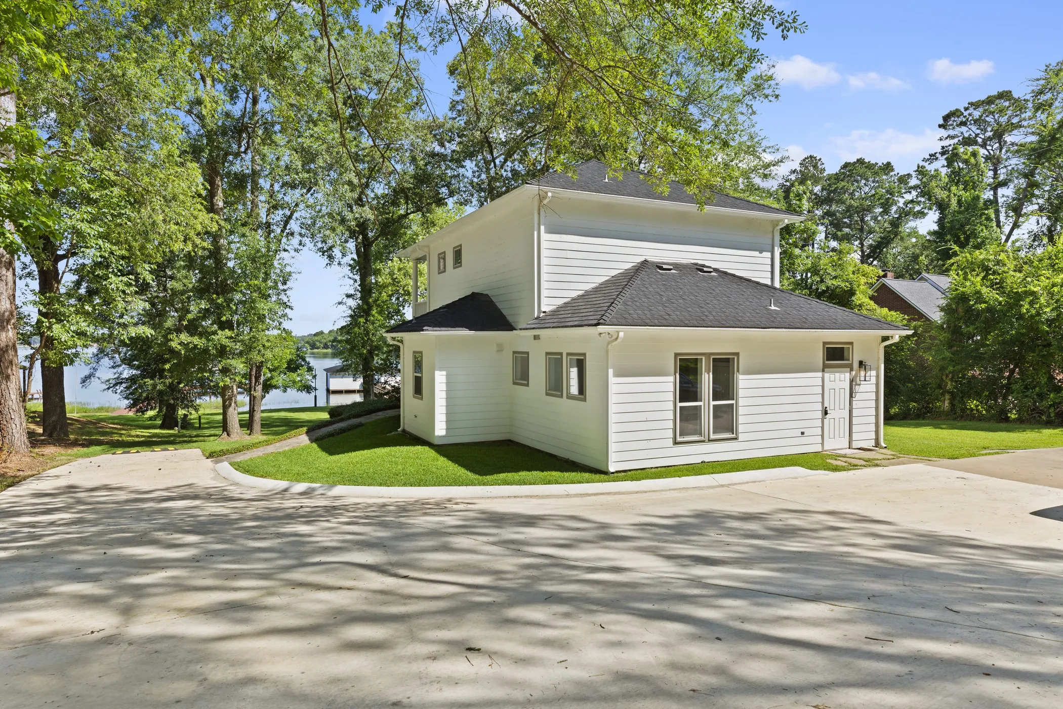 Modern farmhouse-style residence featuring clean white exterior siding, a pitched roof with dark shingles, and a wraparound design