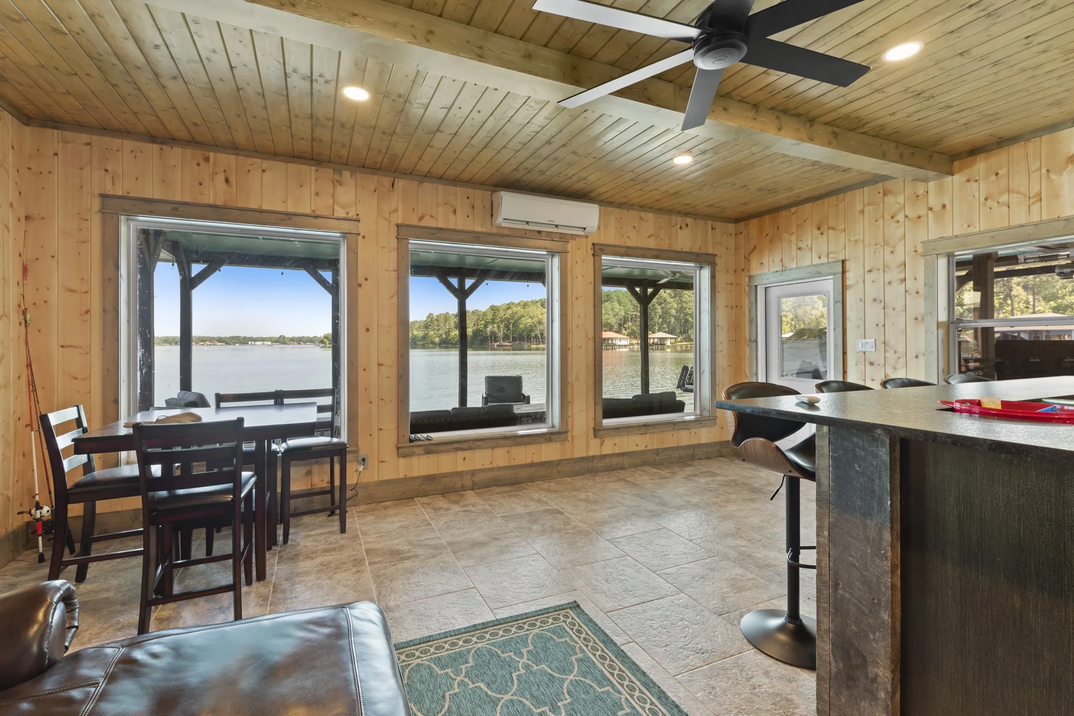 Wood-paneled room with multiple large windows overlooking a body of water