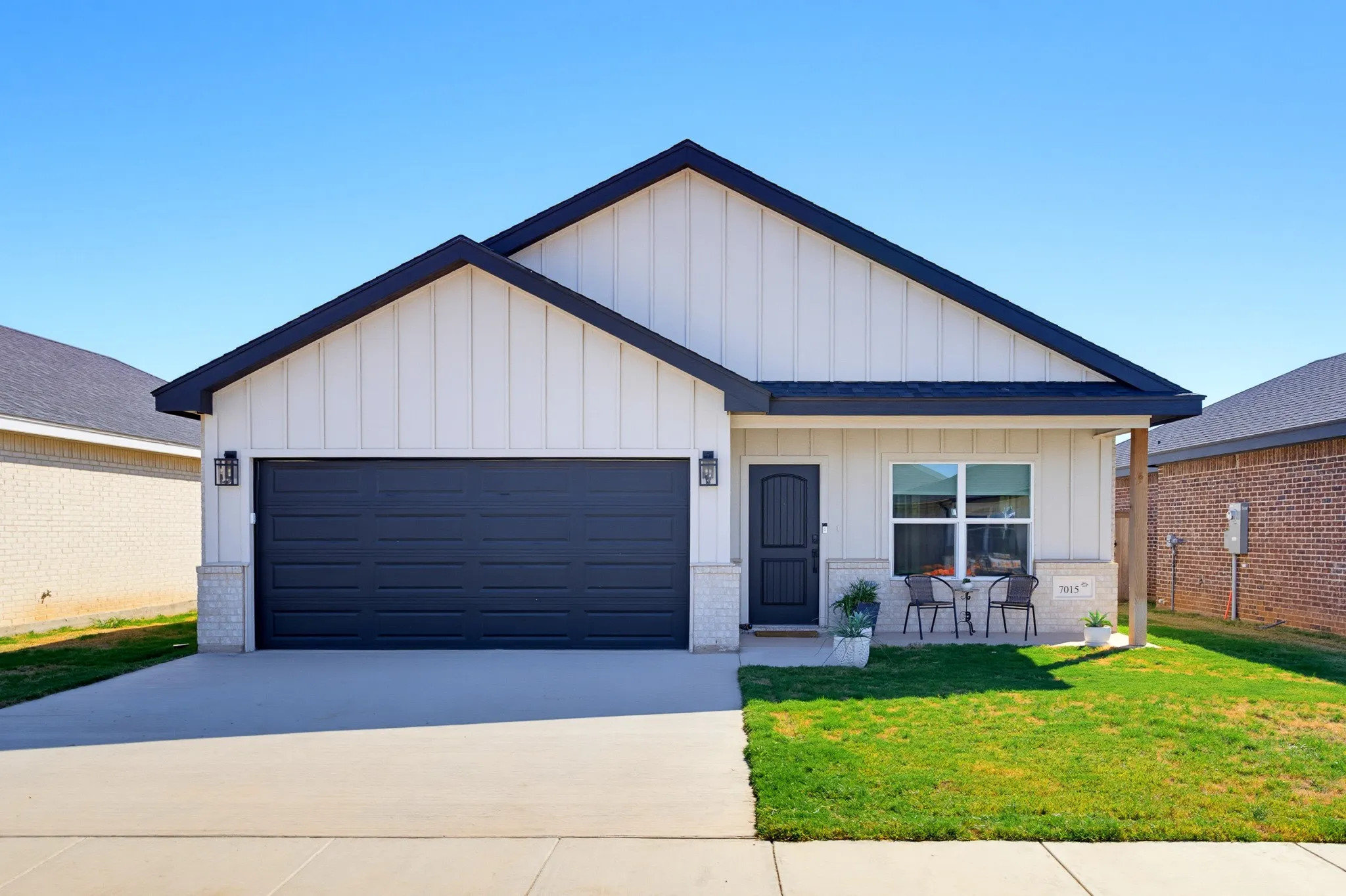 Contemporary exterior with vertical panel siding, dark-toned garage door, stone accents, and a covered entry