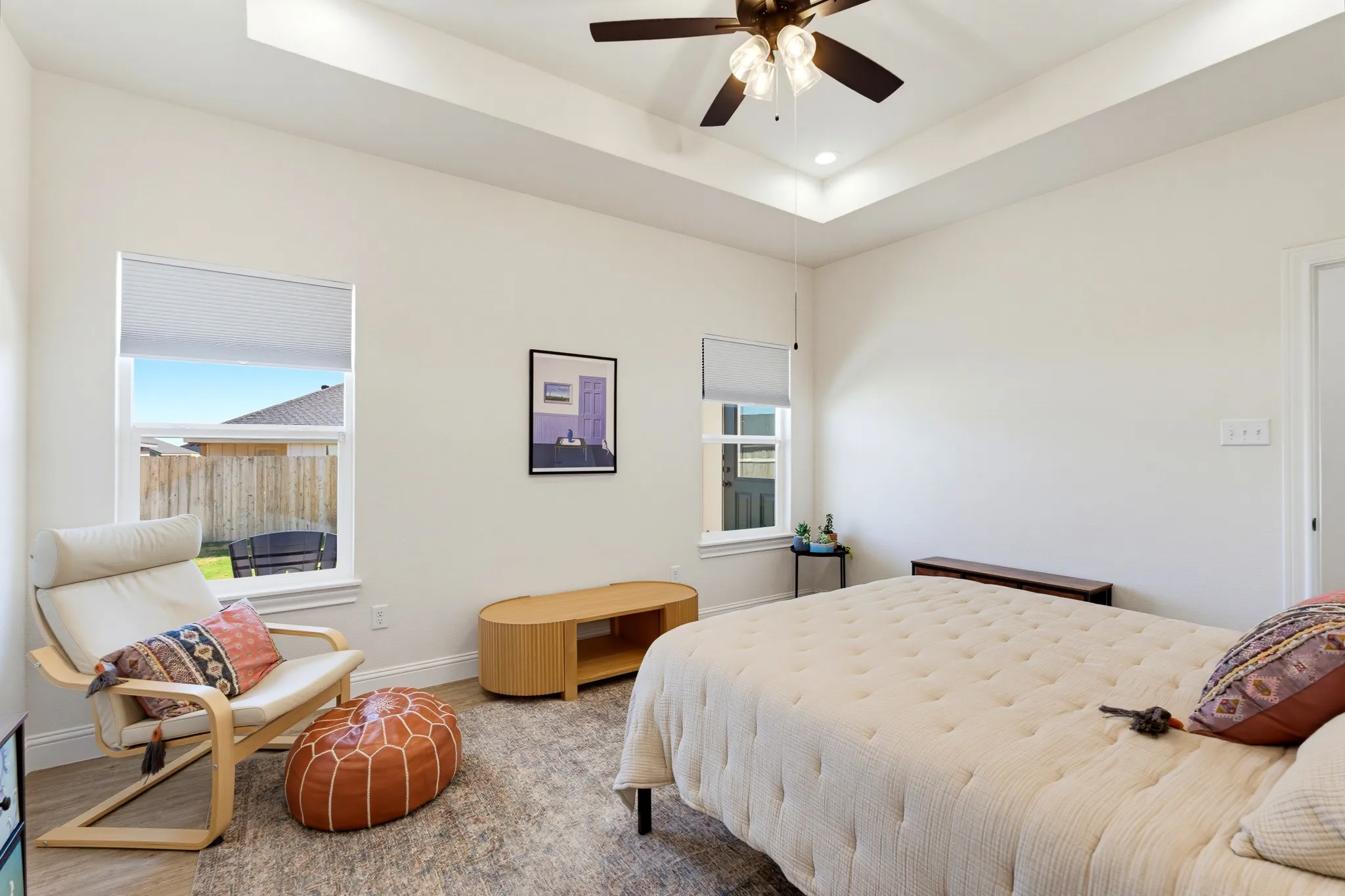 Tray ceiling with recessed lighting and a ceiling fan, dual windows, and wood-finish flooring