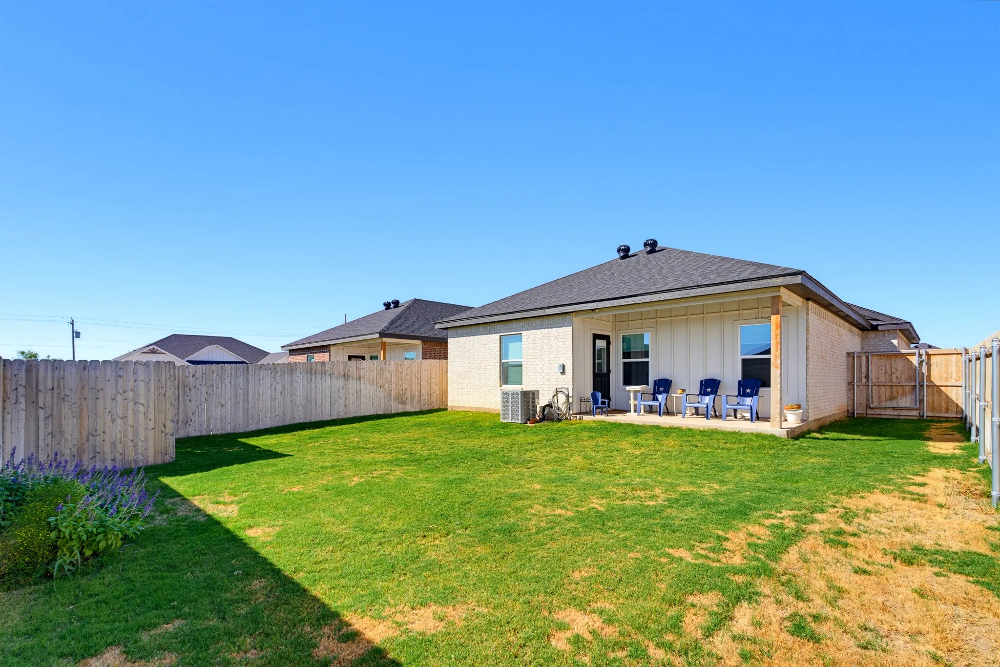 Expansive backyard with a manicured lawn, full privacy fencing, and a concrete patio