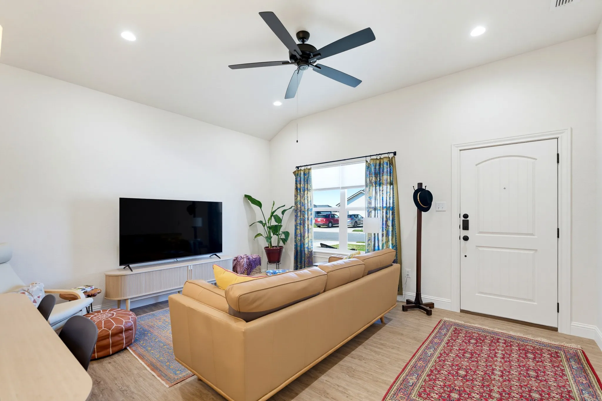 Vaulted ceiling with recessed lighting and a ceiling fan, wood-finish flooring, and a white paneled entrance door
