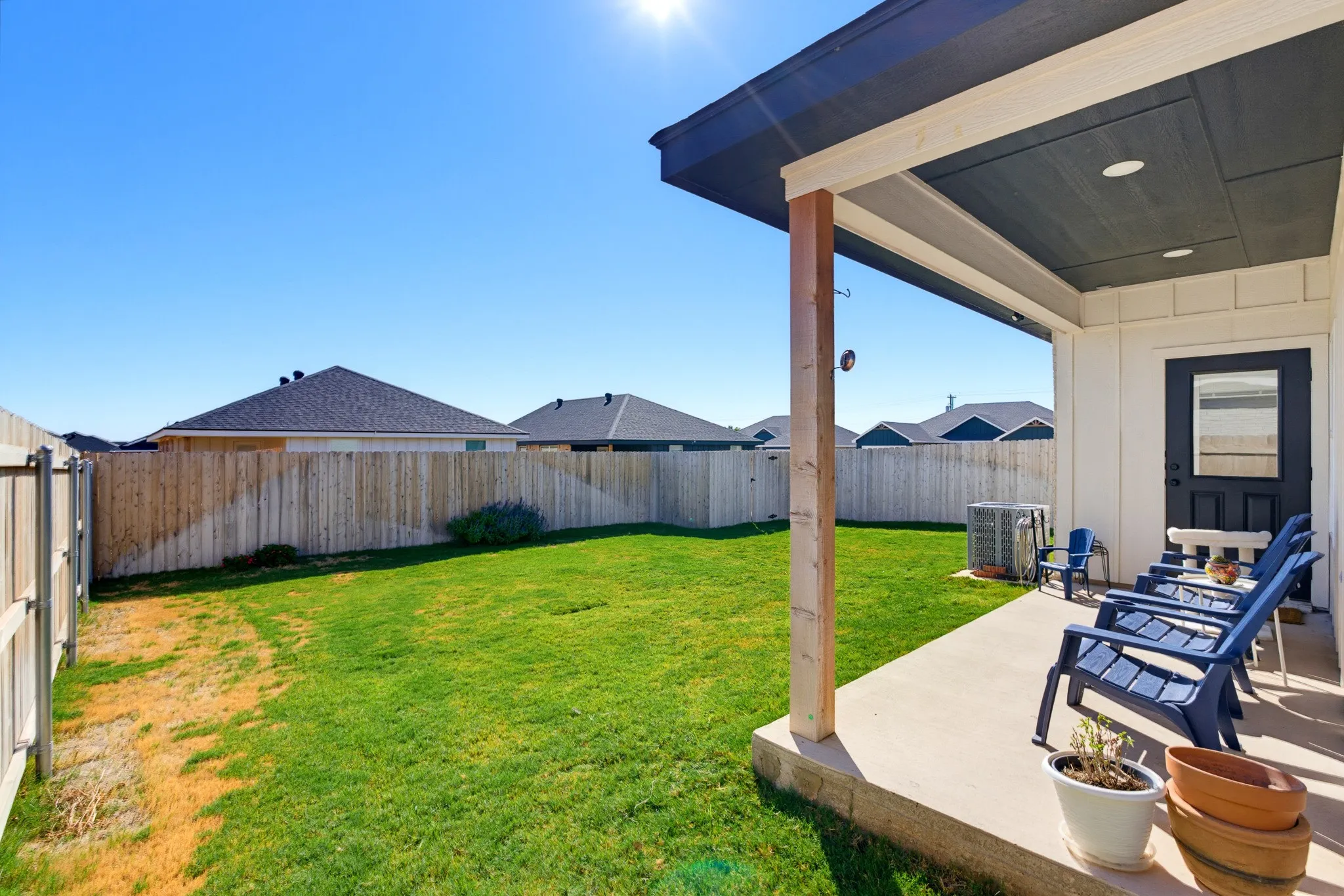 Expansive backyard featuring a manicured lawn, wood-finished pergola with integrated ceiling, concrete patio, and wooden privacy fencing