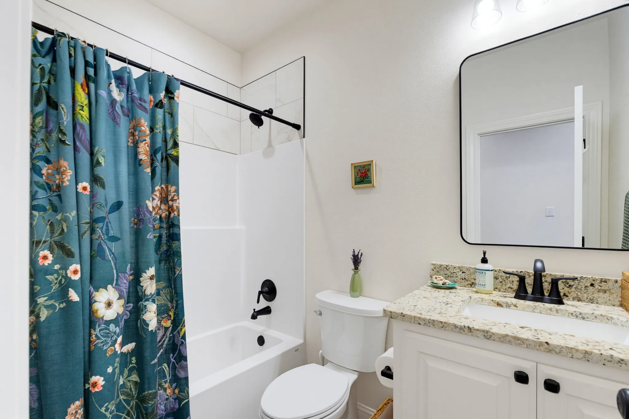 White vanity with granite countertop and black faucet