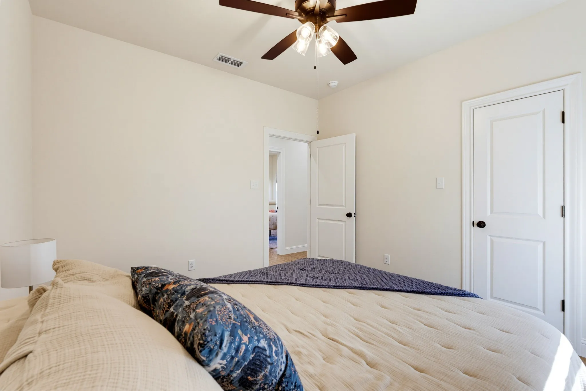 Neutral tone walls with white trim, a ceiling fan with integrated lighting, and a paneled door with black hardware