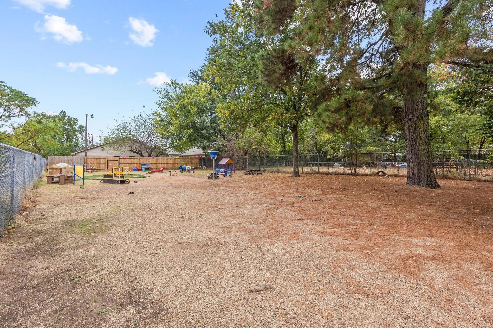 Expansive outdoor area featuring mature trees and a chain-link fence