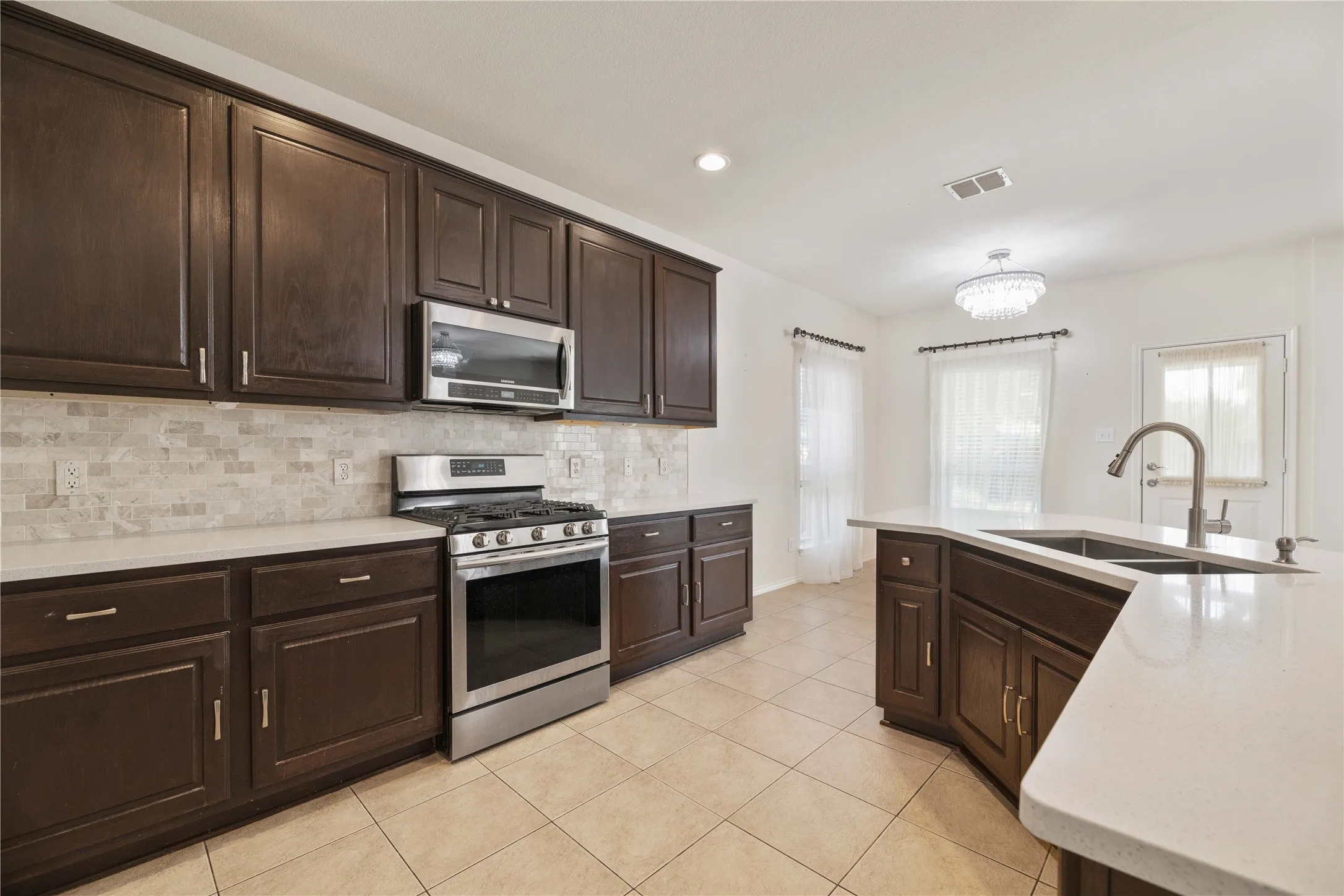 Spacious kitchen featuring dark wood cabinetry with stainless steel appliances, including a gas range and microwave