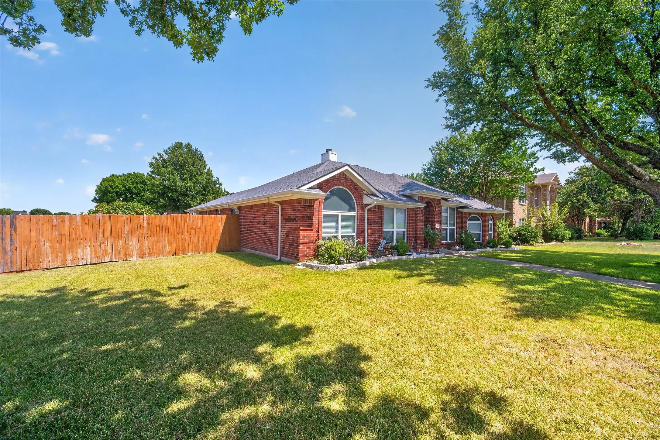 Red brick exterior with white trim, arched windows, and a dark roof