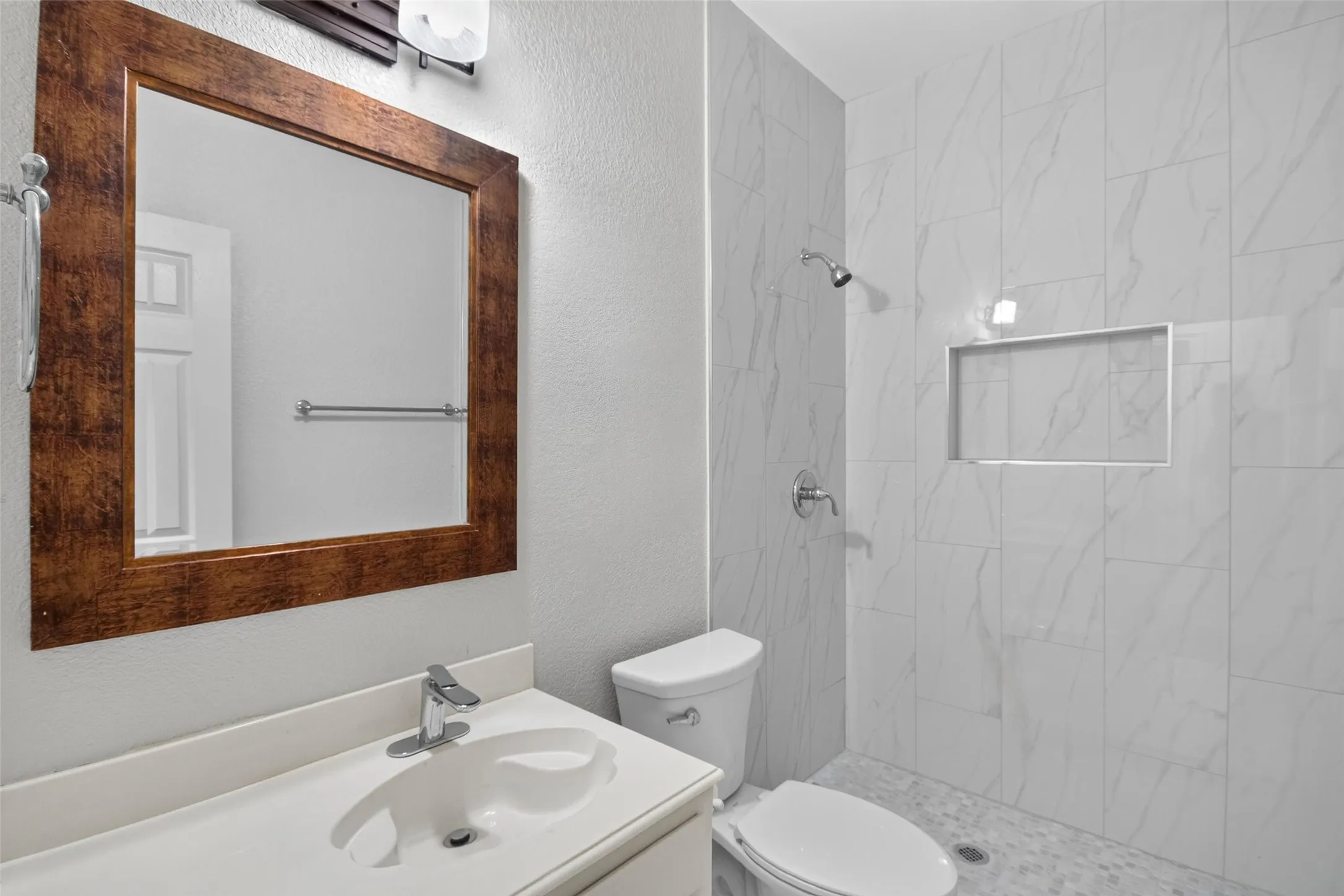 Vanity with white countertop and integrated sink, chrome faucet, and framed mirror