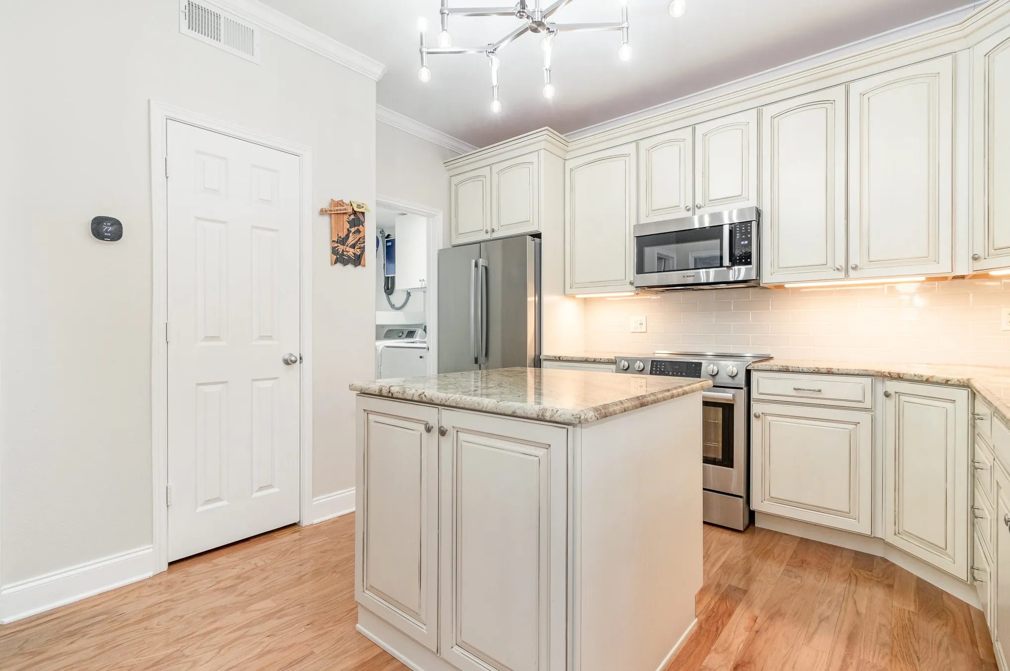 Full-size utility room off kitchen to the left of fridge provides efficient location.