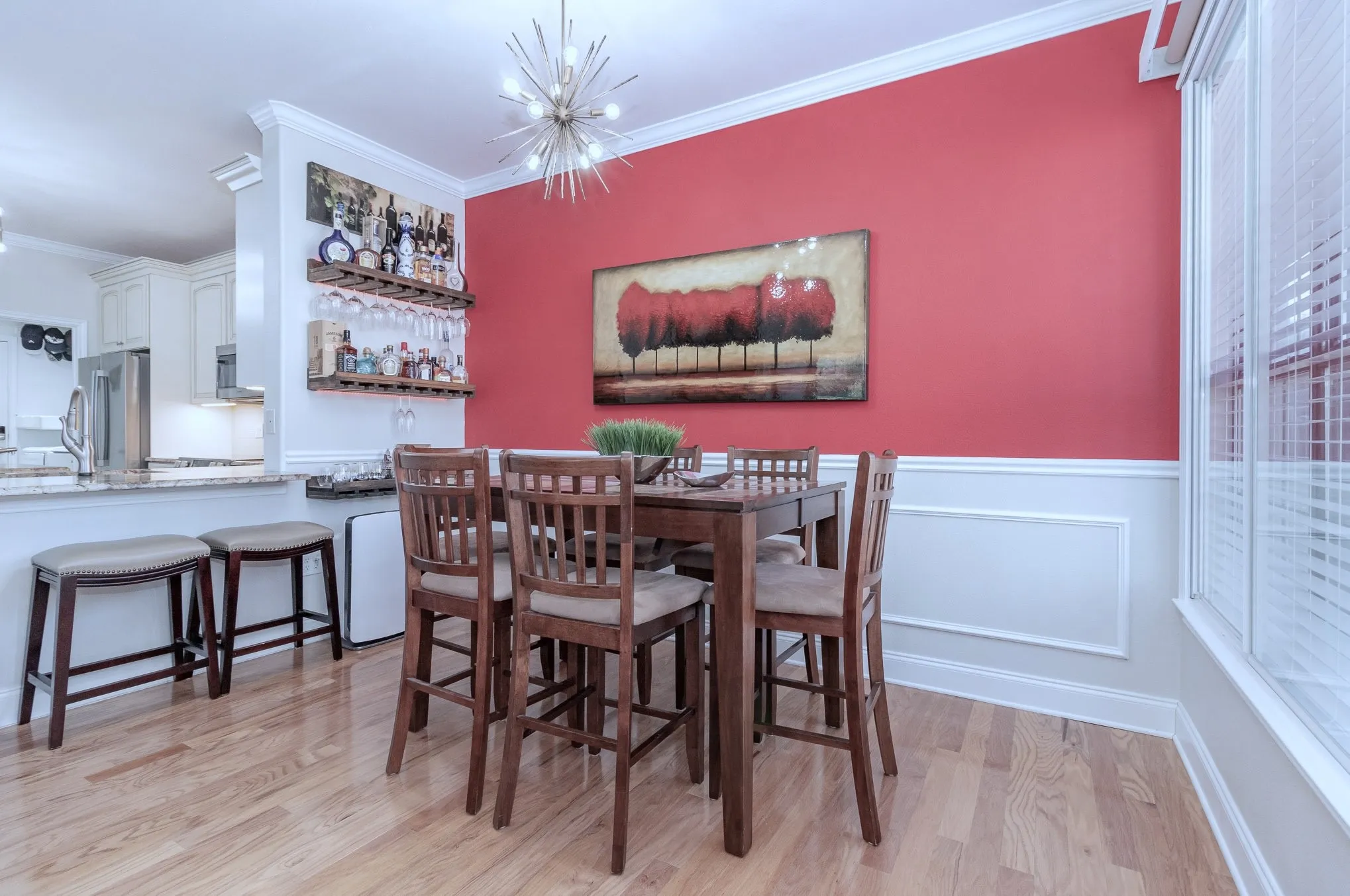 Dining area with built-in shelving, wainscoting and picture frame paneling. Crown-molding accents. Designer light fixture.