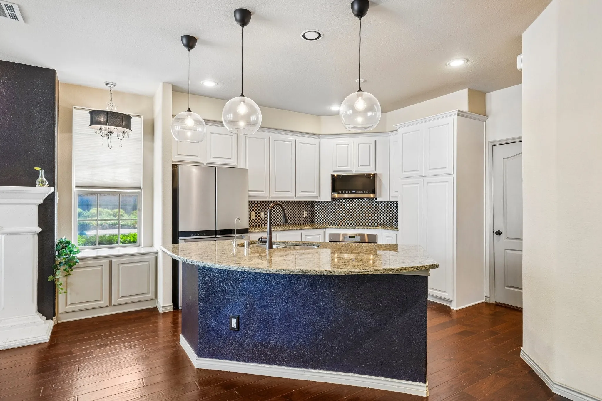 Kitchen island with a light-toned countertop, dark wood-finish flooring, white cabinetry, a dark mosaic tile backsplash, and stainless steel appliances