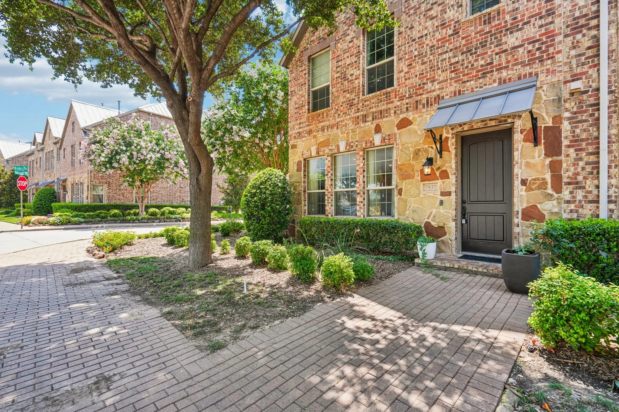 Brick and stone exterior with a dark paneled entry door and metal awning