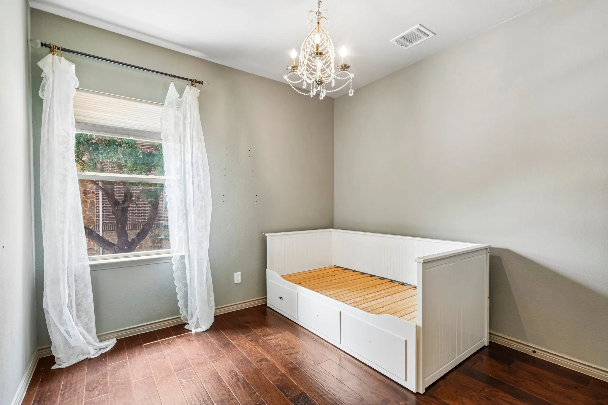 Hardwood-style flooring, white built-in daybed with integrated storage, single window with blinds, and a decorative chandelier